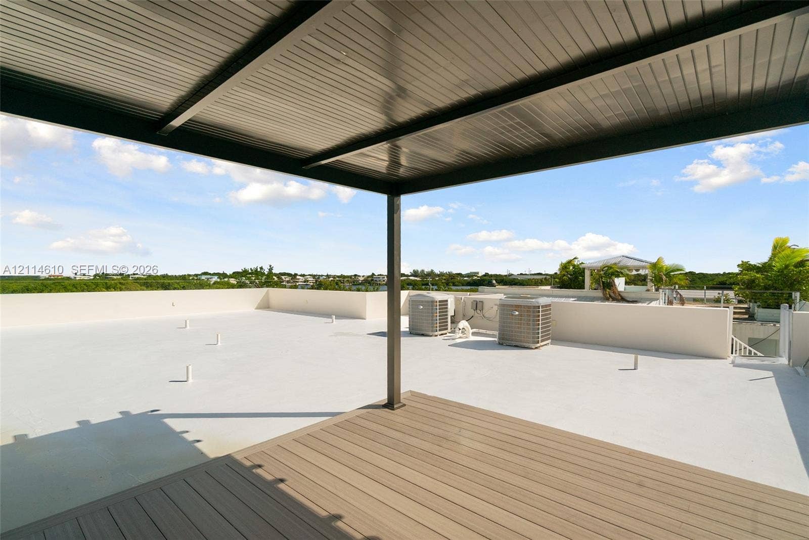 131 Ojibway Avenue, Islamorada, FL 33070 Expansive rooftop terrace featuring a composite wood-finish deck, covered metal pergola, solid perimeter walls, and glass balustrade railing