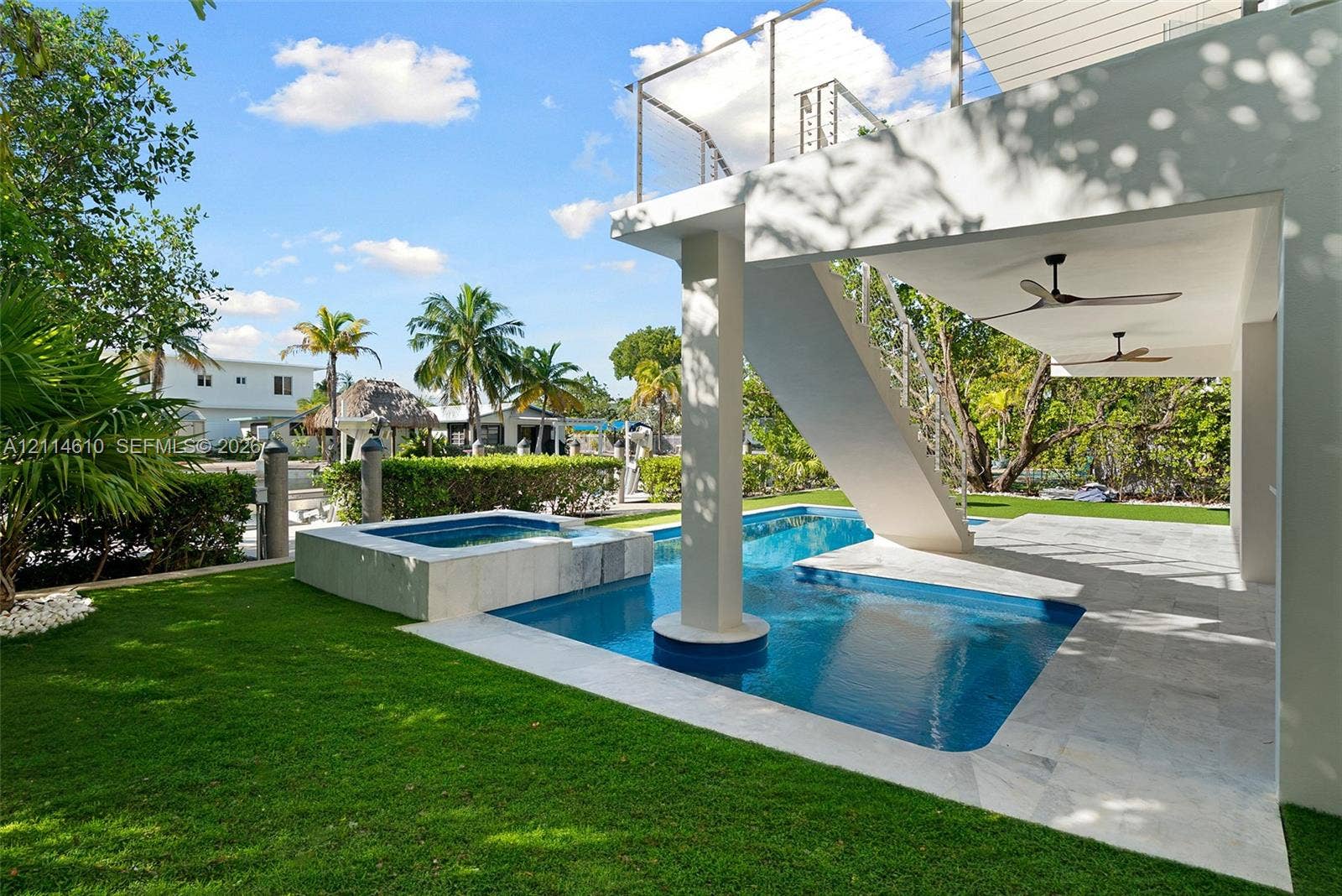 131 Ojibway Avenue, Islamorada, FL 33070 Swimming pool with integrated spa, covered patio with ceiling fans, and manicured lawn