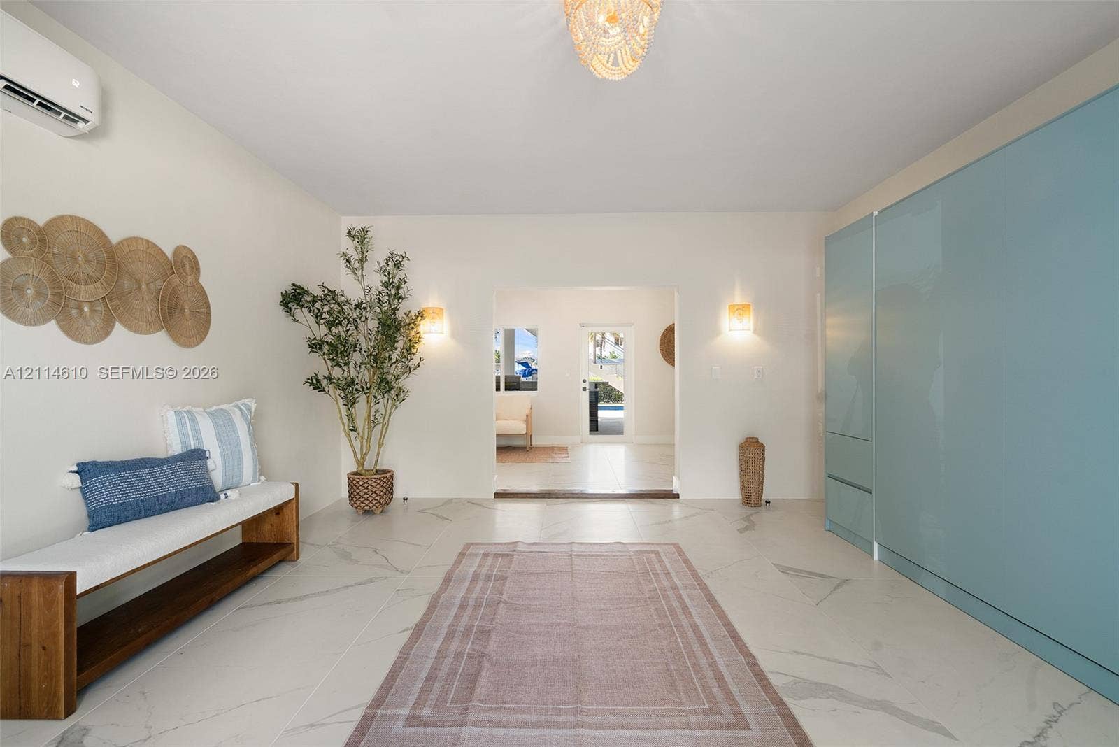 131 Ojibway Avenue, Islamorada, FL 33070 Large-format tile flooring with marble-style veining, floor-to-ceiling high-gloss panel cabinetry, wall-mounted ductless climate control system, tiered beaded chandelier, and dual wall-mounted light fixtures