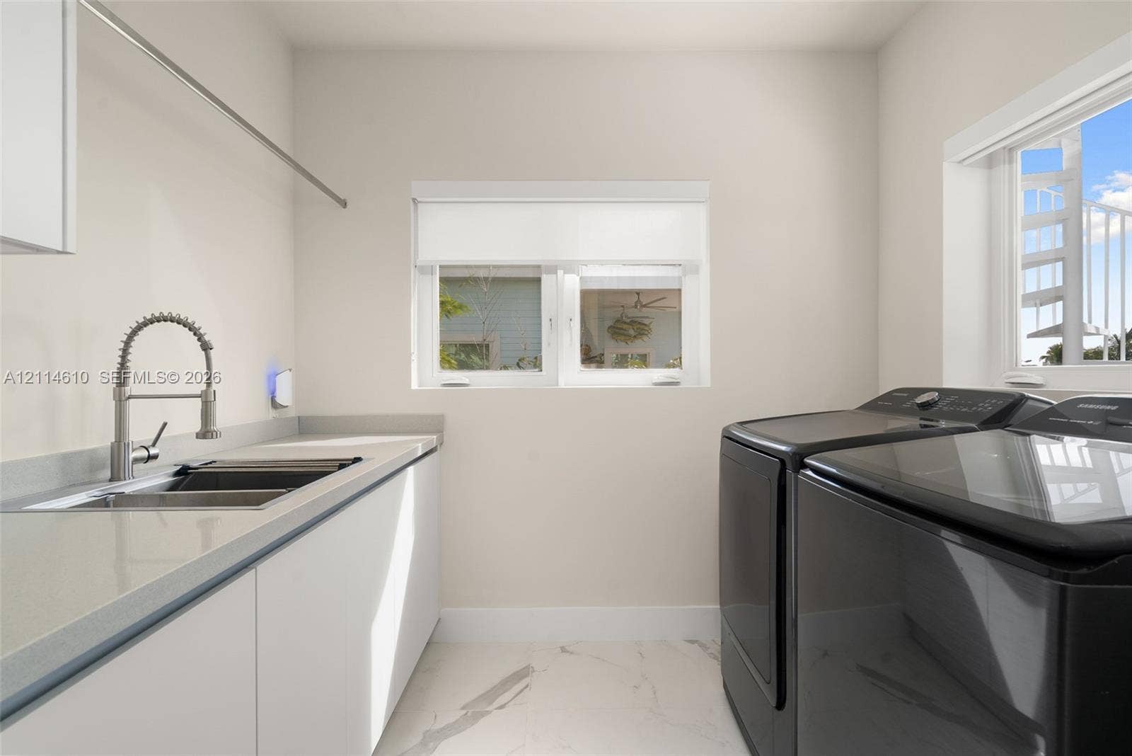 131 Ojibway Avenue, Islamorada, FL 33070 Utility space featuring stone-composite countertops, stainless steel sink with high-arc gooseneck faucet, flat-panel cabinetry, and large-format tile flooring