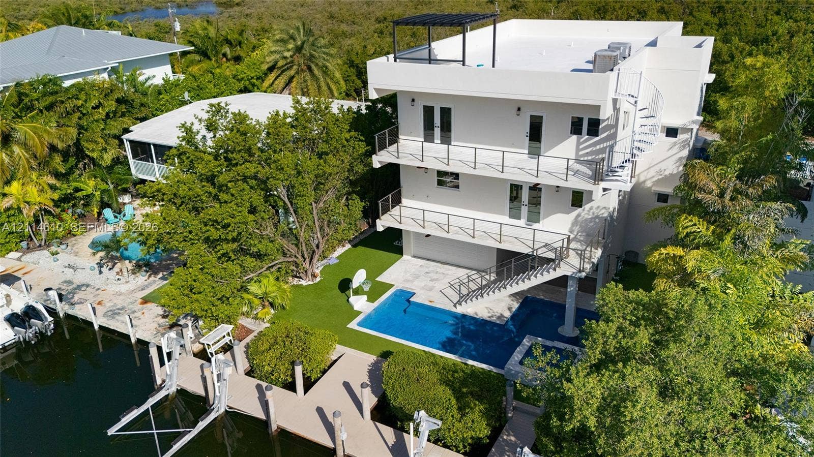 131 Ojibway Avenue, Islamorada, FL 33070 Three-story waterfront residence featuring multi-level balconies, a private boat dock, an in-ground swimming pool, and a rooftop deck