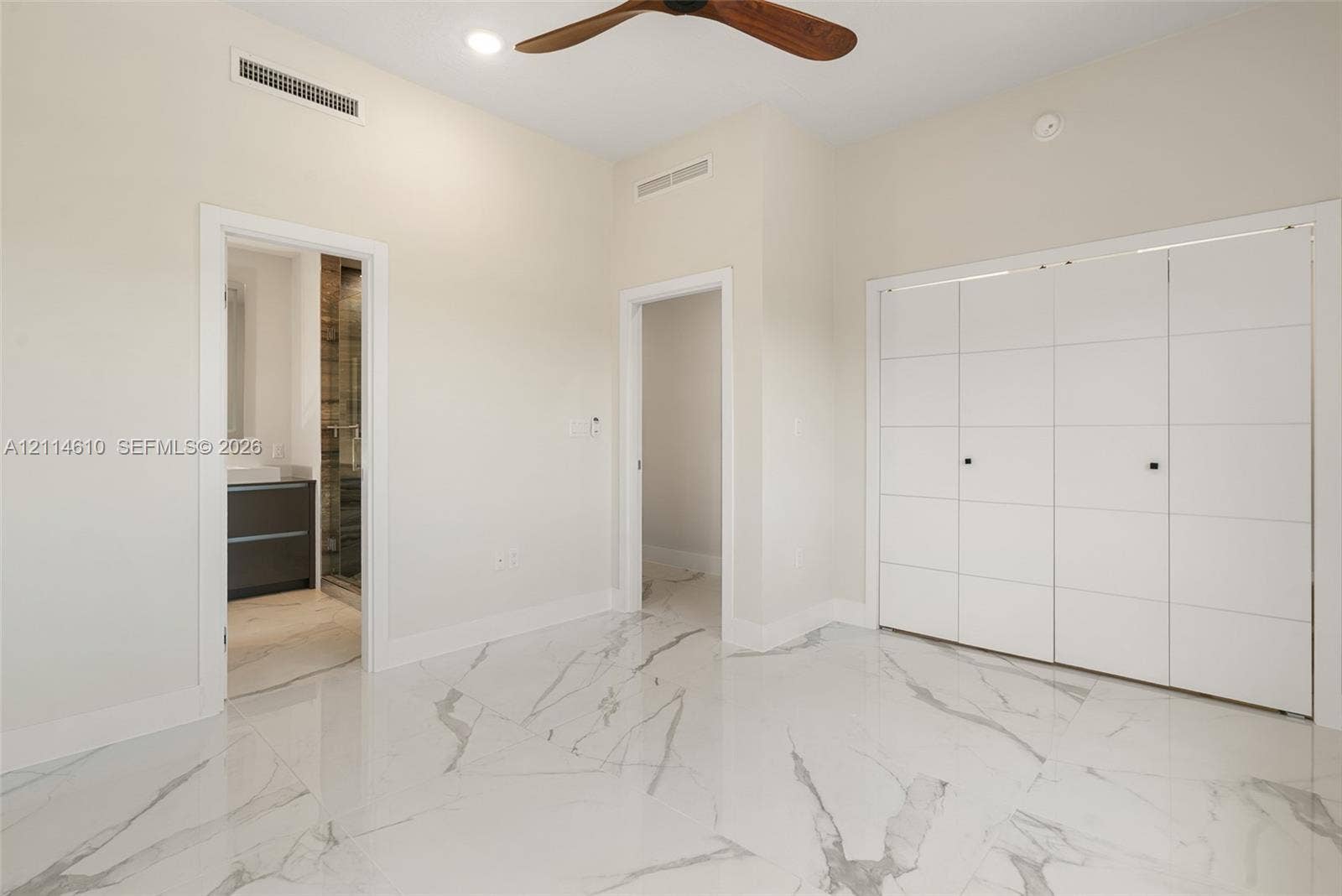 131 Ojibway Avenue, Islamorada, FL 33070 High-gloss porcelain tile flooring with marble-pattern veining, floor-to-ceiling multi-panel white cabinetry, and a ceiling fan with wood-finish blades