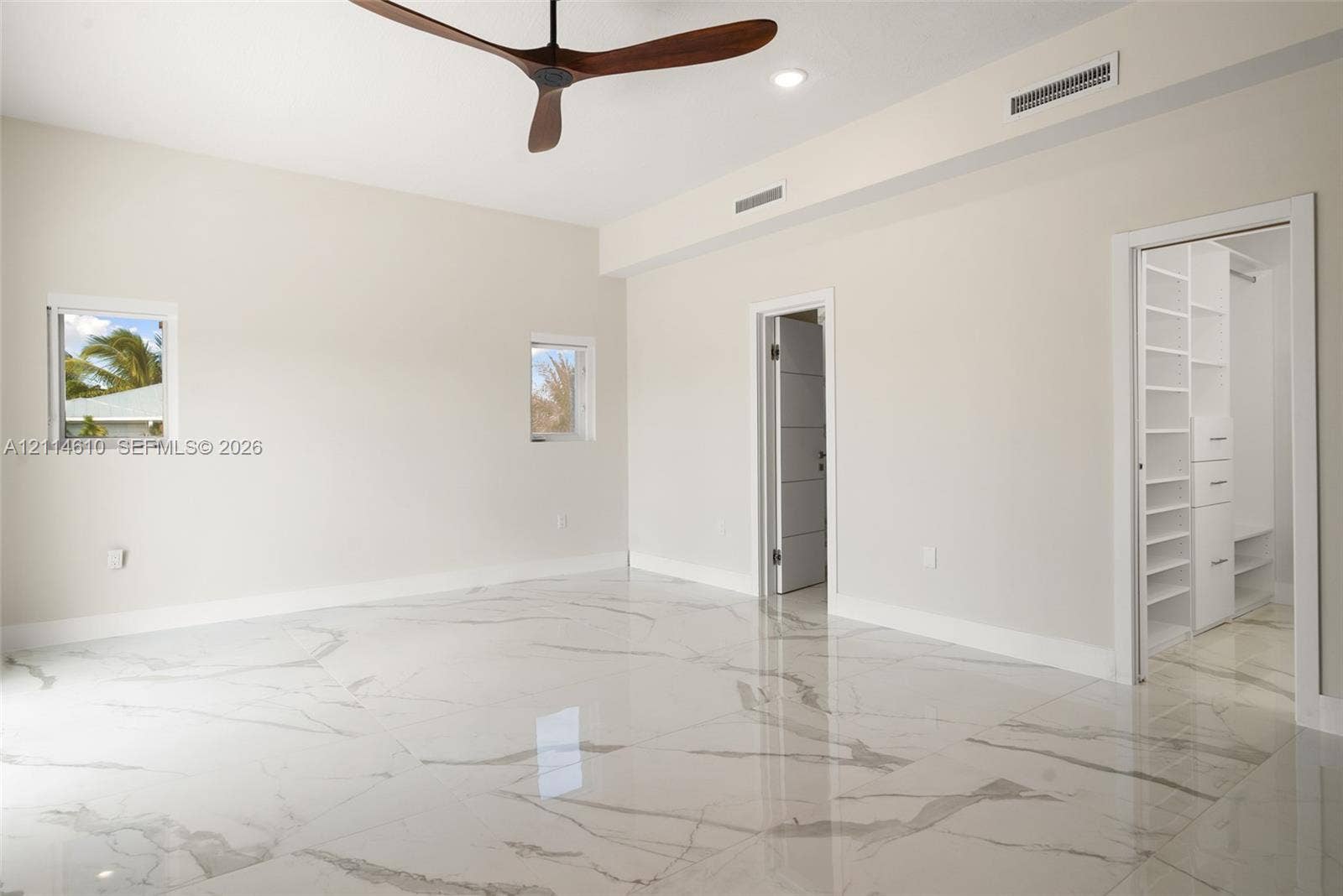 131 Ojibway Avenue, Islamorada, FL 33070 Polished stone-finish flooring featuring large-format veining, high ceilings, ceiling fan with aerodynamic blades, recessed lighting, and built-in walk-in closet shelving