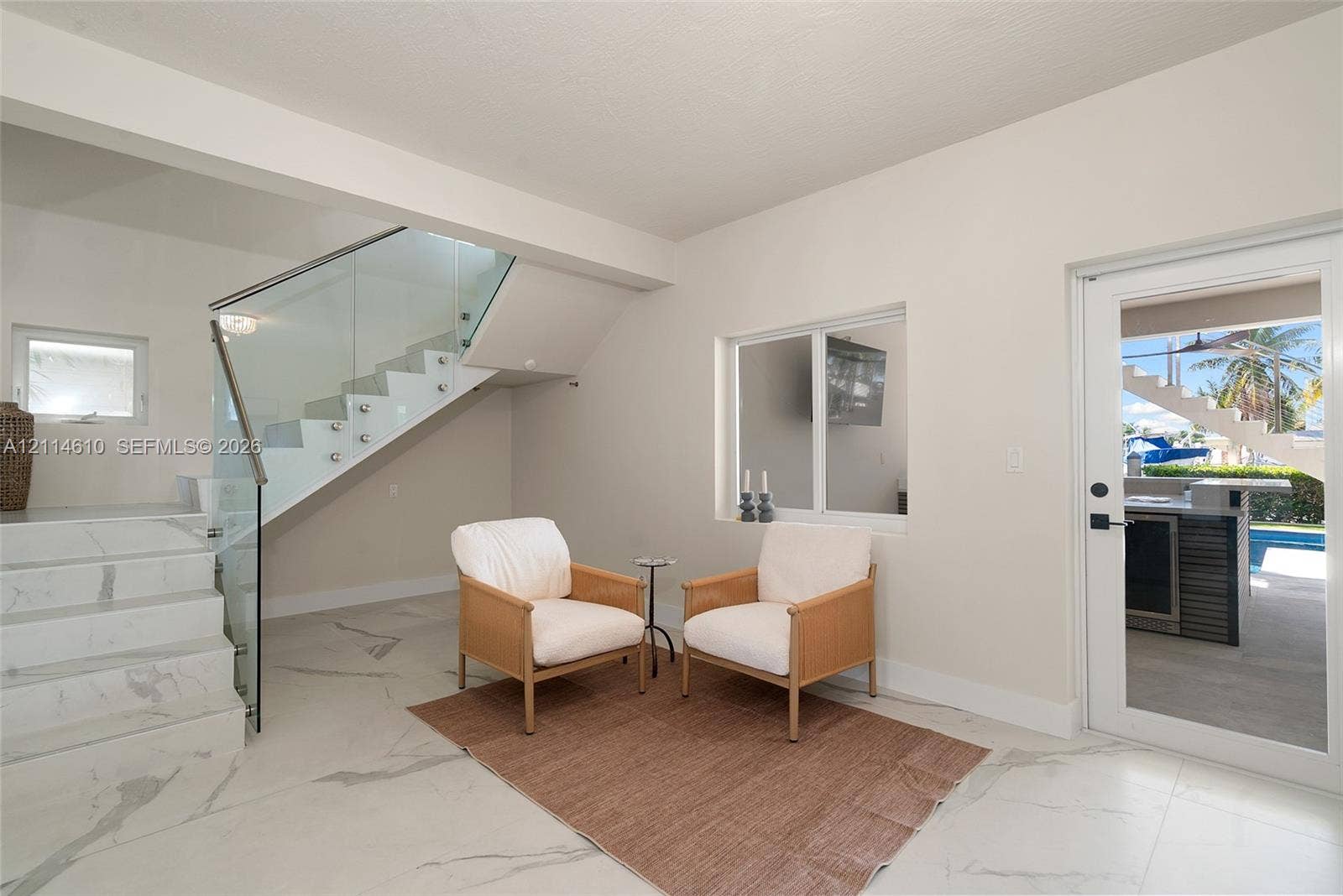 131 Ojibway Avenue, Islamorada, FL 33070 Large-format stone flooring, staircase with glass railing and stainless steel standoffs, and full-glass exterior door