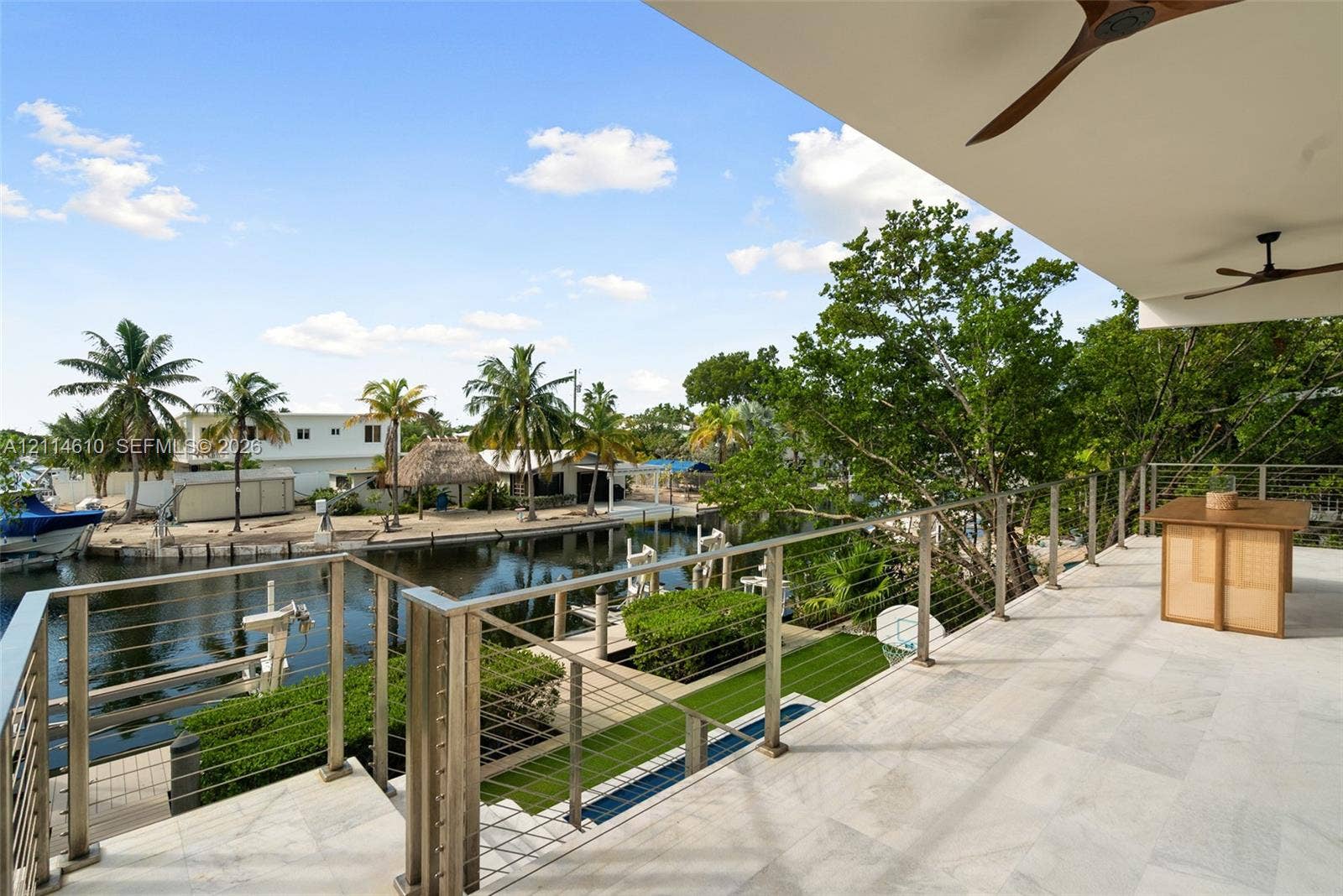 131 Ojibway Avenue, Islamorada, FL 33070 Covered balcony featuring stone flooring, stainless steel railing with cable infill, and ceiling-mounted fans