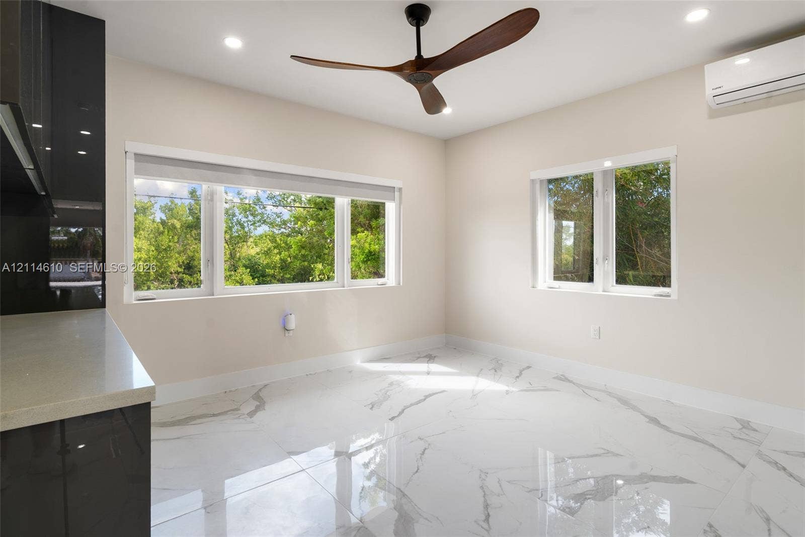 131 Ojibway Avenue, Islamorada, FL 33070 Polished tile flooring with veining, three-blade ceiling fan, recessed lighting, wall-mounted air conditioning unit, and large windows with greenery exposure