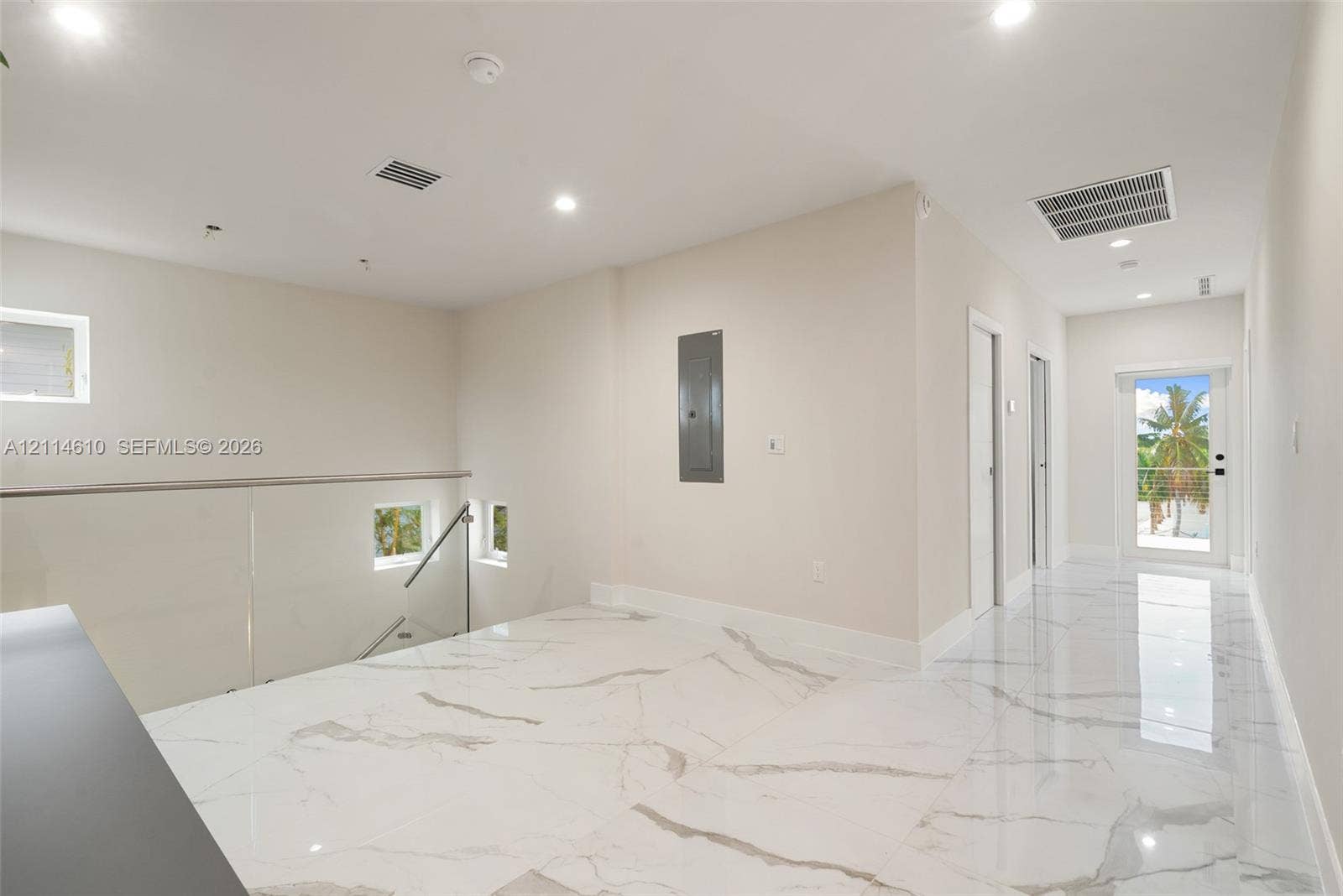 131 Ojibway Avenue, Islamorada, FL 33070 Large-format white tile flooring with grey veining, recessed lighting, and a glass panel railing with a metallic handrail