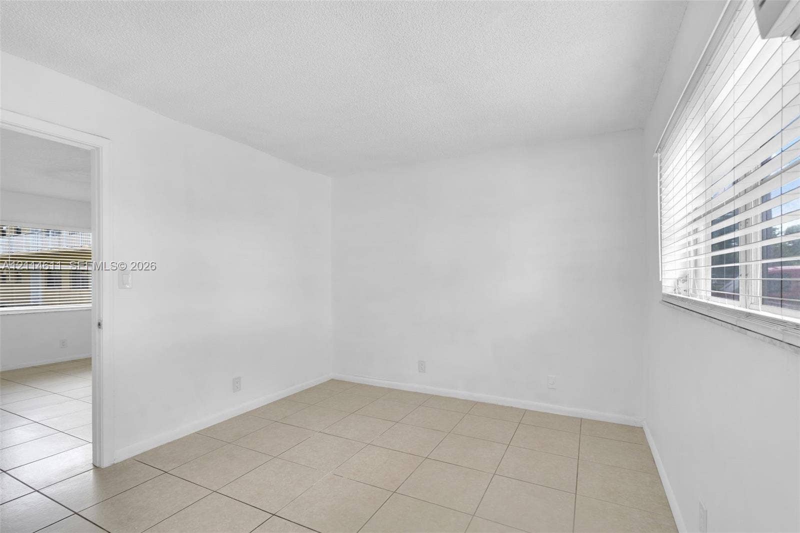 Neutral-toned tile flooring, horizontal window blinds, and solid white wall finishes
