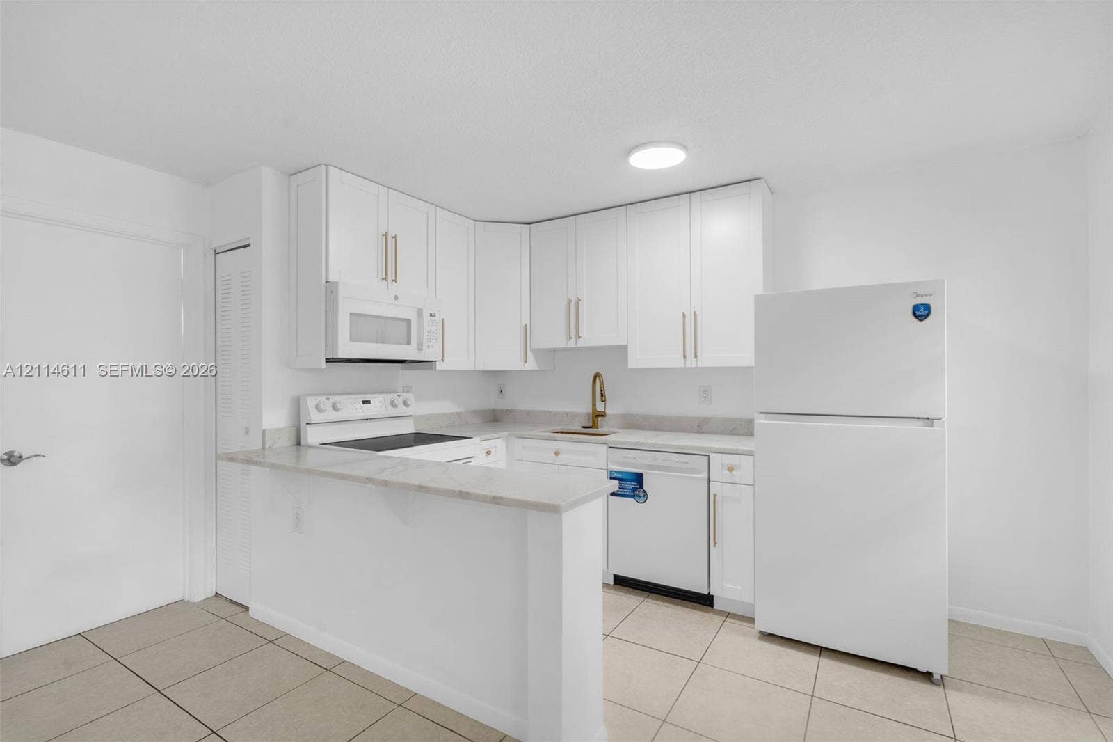Kitchen featuring white cabinetry with metallic hardware, stone-finish countertops, tile flooring, and integrated white appliances