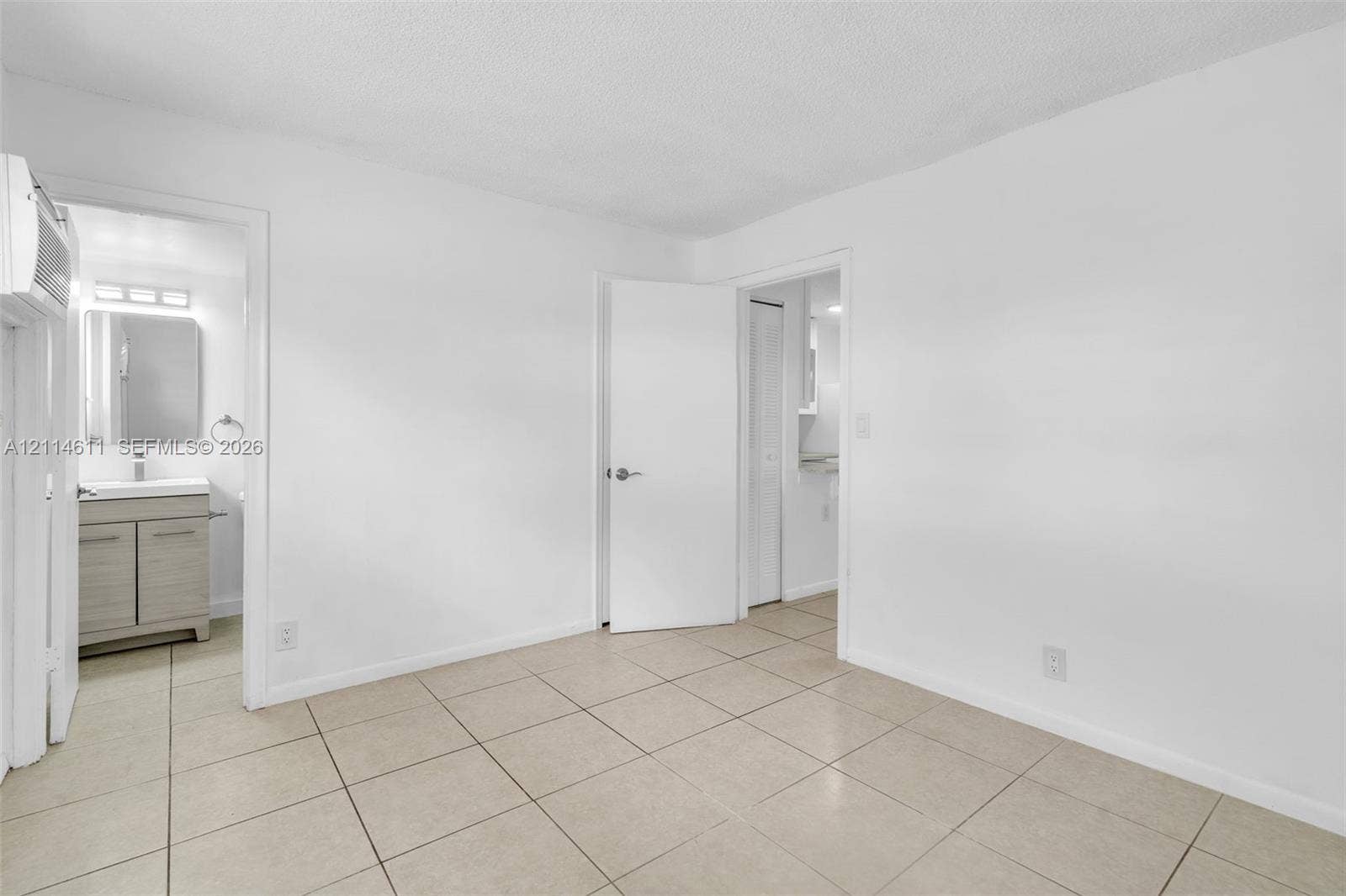 Interior space featuring neutral tile flooring and a vanity with a rectangular sink, stone-finish countertop, and integrated storage cabinetry