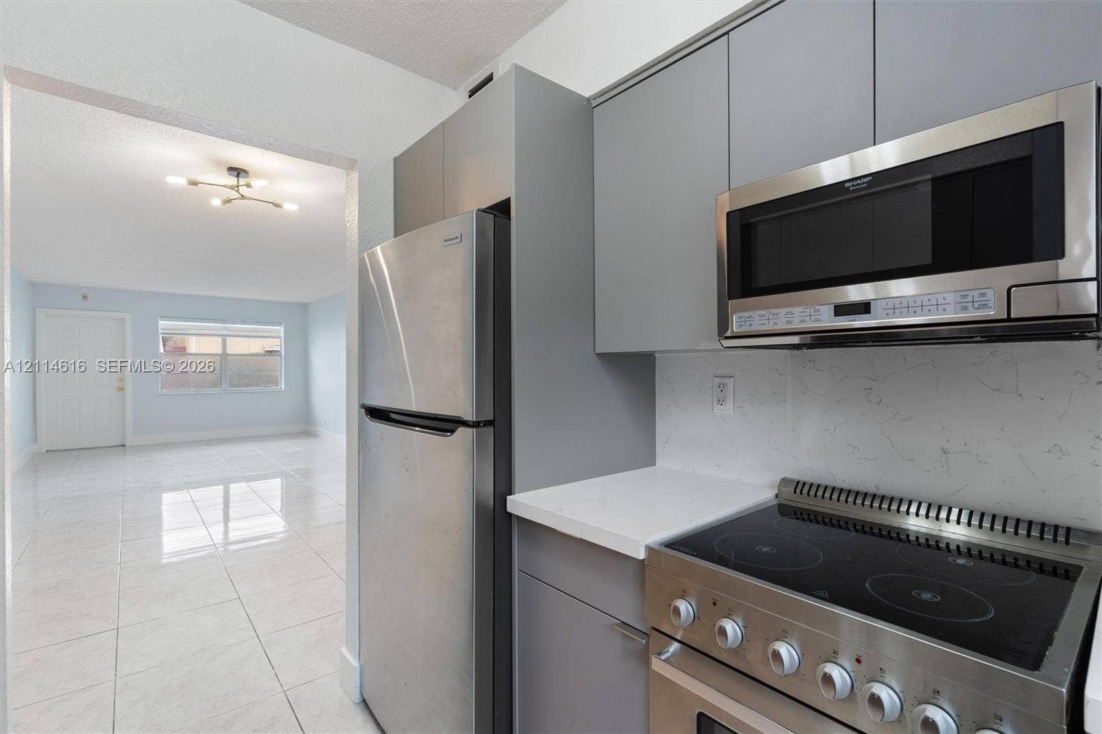 2607 NE 8th Avenue, #35, Wilton Manors, FL 33334 Kitchen featuring grey flat-panel cabinetry, stainless steel appliances, stone-look countertops, and high-gloss tile flooring