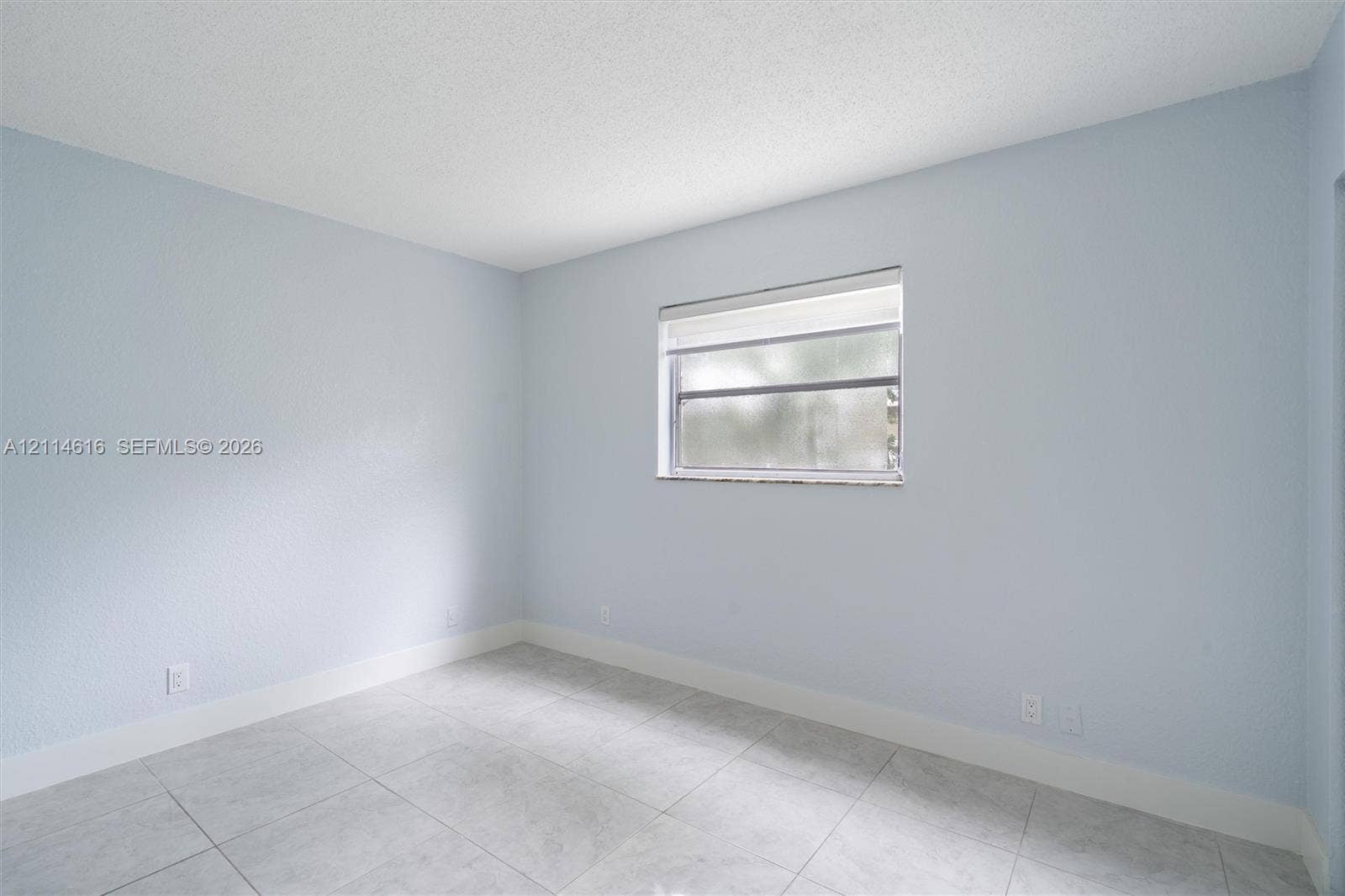 2607 NE 8th Avenue, #35, Wilton Manors, FL 33334 Interior room featuring large-format ceramic tile flooring, neutral wall paint, and a single-hung window with a roller shade