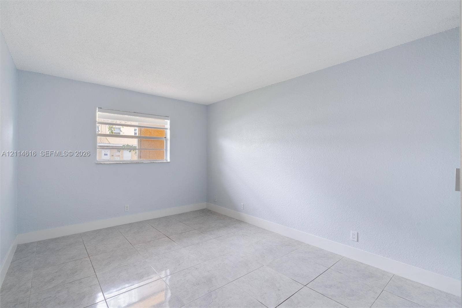 2607 NE 8th Avenue, #35, Wilton Manors, FL 33334 Neutral interior room featuring light-toned wall finishes, large-format tile flooring, and a horizontal louvered window