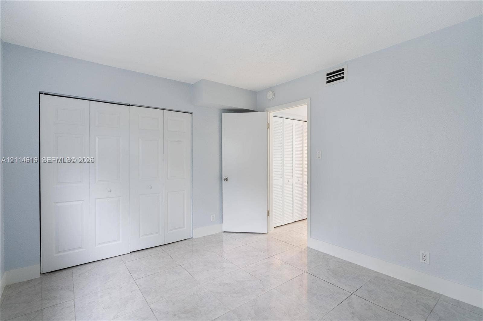 2607 NE 8th Avenue, #35, Wilton Manors, FL 33334 Interior space featuring neutral wall tones, large-format tile flooring, and integrated white bi-fold closet doors