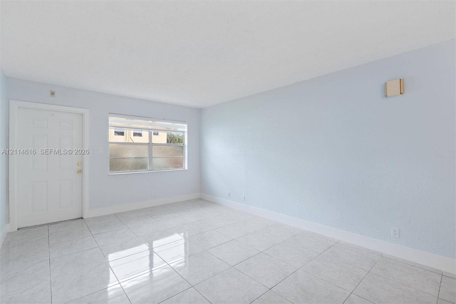 2607 NE 8th Avenue, #35, Wilton Manors, FL 33334 Interior room featuring large-format tile flooring, light-toned wall paint, a six-panel exterior door, and a horizontal sliding window