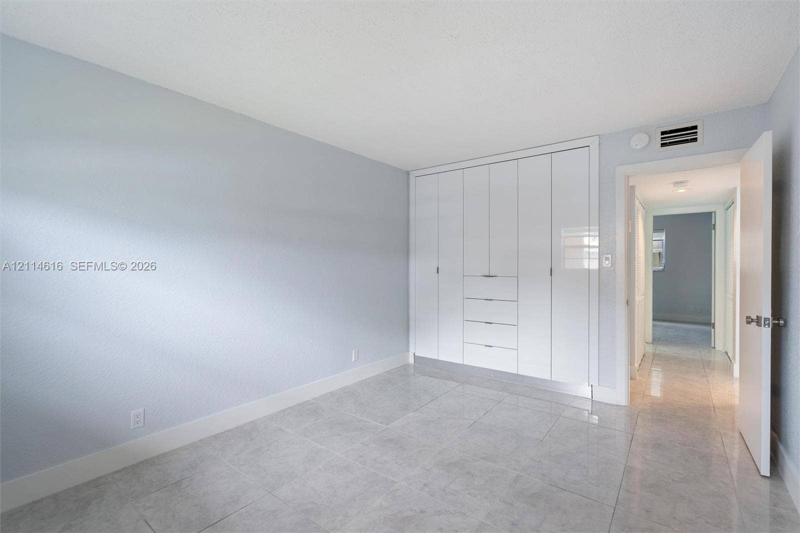 2607 NE 8th Avenue, #35, Wilton Manors, FL 33334 Neutral-toned room featuring large-format tile flooring and floor-to-ceiling built-in white cabinetry with integrated drawer storage