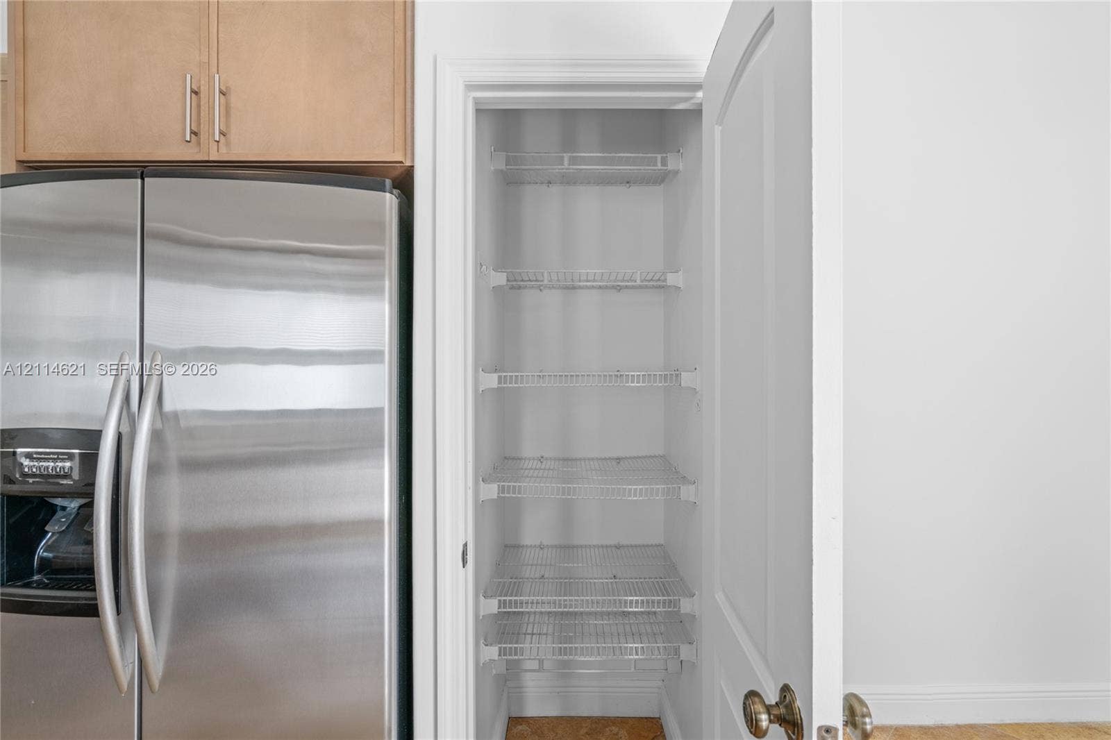 8978 NW 152nd Lane, #8978, Miami Lakes, Miami Lakes, FL 33018 Pantry featuring multi-level wire shelving and a traditional hinged door, positioned beside stainless steel refrigeration and wood-finish cabinetry