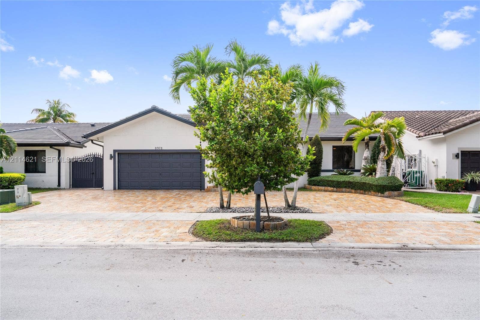 8978 NW 152nd Lane, #8978, Miami Lakes, Miami Lakes, FL 33018 Single-story exterior featuring a light-toned stucco faade, a multi-car garage with a paneled door, a paved driveway, a tile roof, and curated tropical landscaping