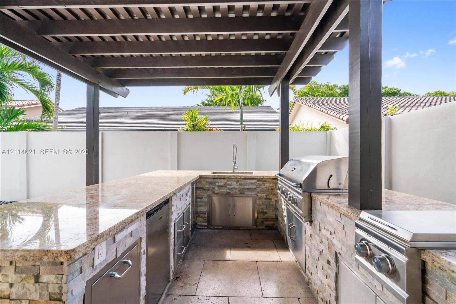 8978 NW 152nd Lane, #8978, Miami Lakes, Miami Lakes, FL 33018 Outdoor kitchen featuring a stone-clad base, built-in stainless steel grill, stone countertop, undermount sink, and overhead pergola