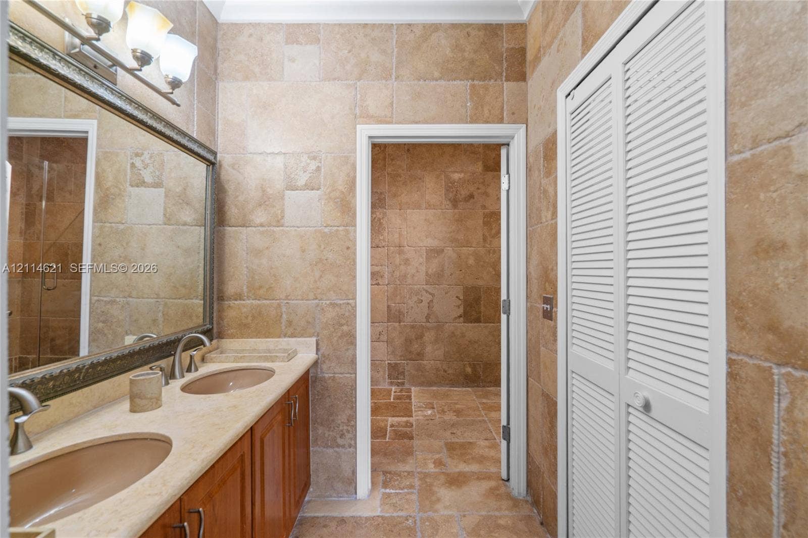 8978 NW 152nd Lane, #8978, Miami Lakes, Miami Lakes, FL 33018 Natural stone tile wall and floor surfaces, dual-basin vanity with a stone countertop, framed wall mirror, and louvered-style closet doors