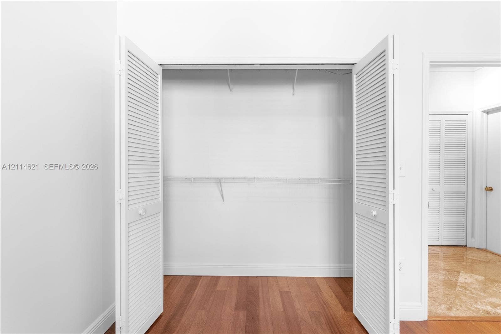 8978 NW 152nd Lane, #8978, Miami Lakes, Miami Lakes, FL 33018 Storage area featuring dual white louvered bi-fold doors, wood-finish flooring, and integrated wire shelving