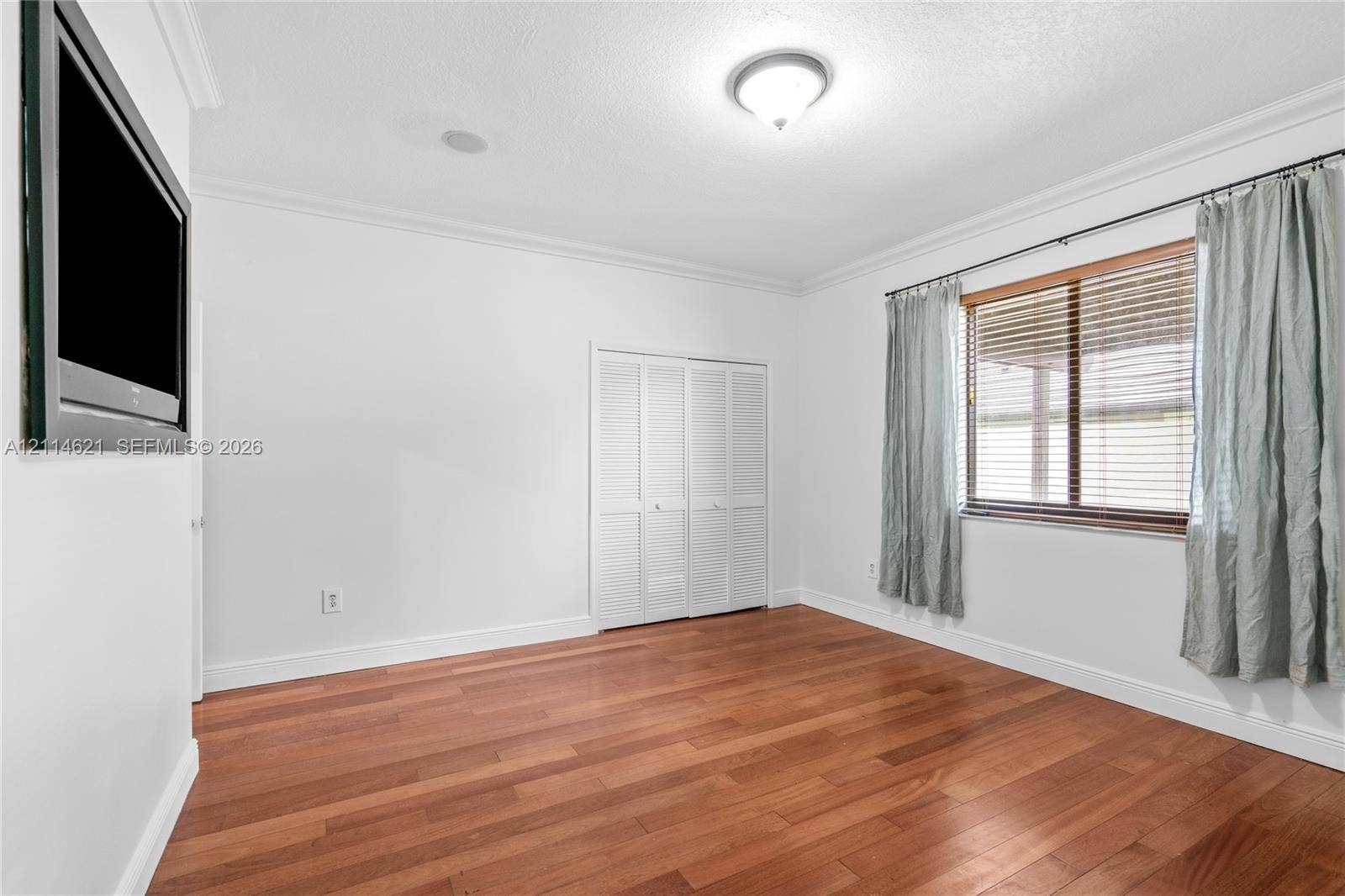 8978 NW 152nd Lane, #8978, Miami Lakes, Miami Lakes, FL 33018 Room featuring wood-finish flooring, crown molding, a flush-mount ceiling light fixture, and a multi-panel closet with louvered doors