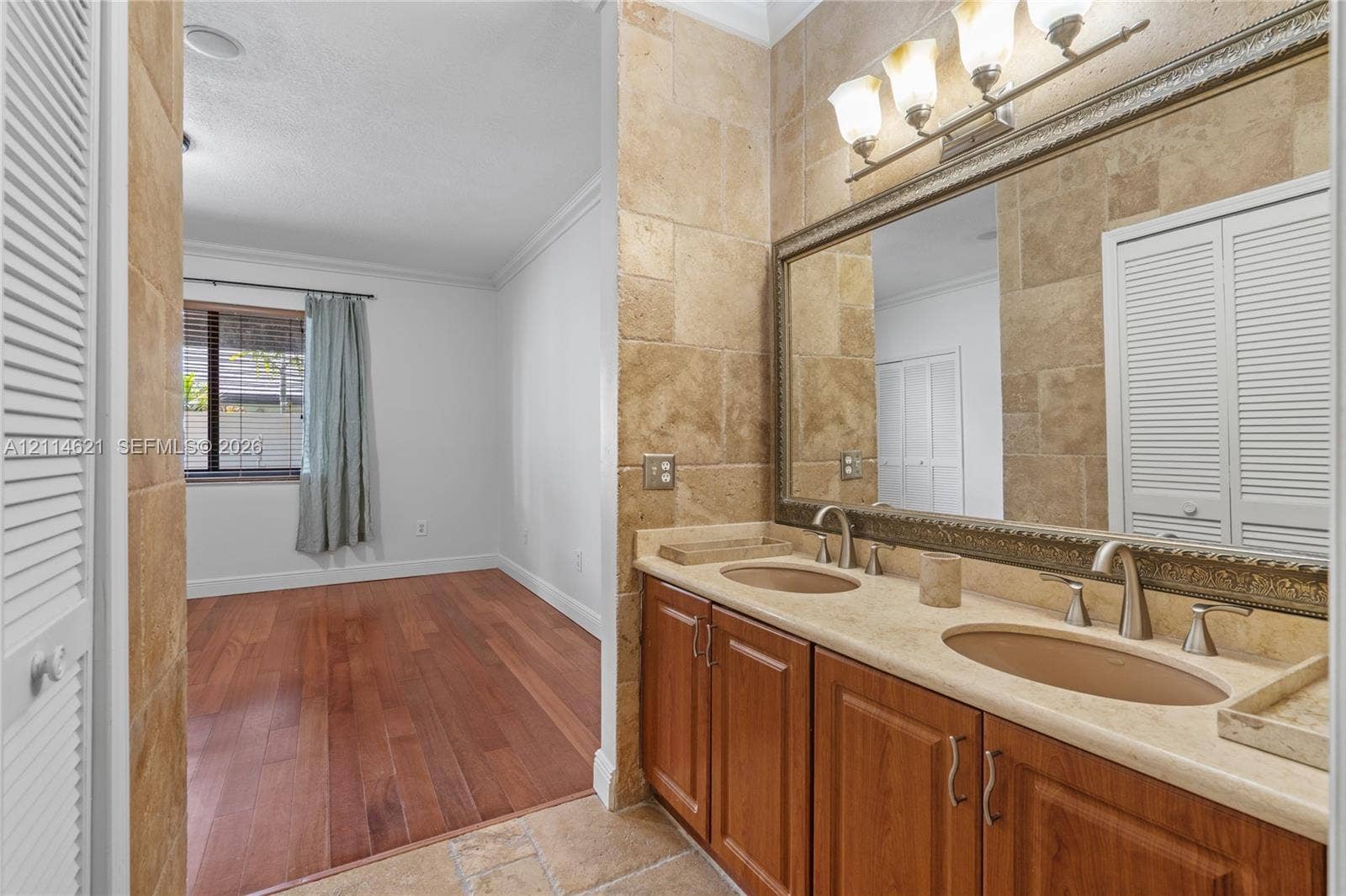 8978 NW 152nd Lane, #8978, Miami Lakes, Miami Lakes, FL 33018 Double vanity with stone-style countertop and undermount sinks, wood-finish cabinetry, tile wall surround, and three-light decorative vanity fixture