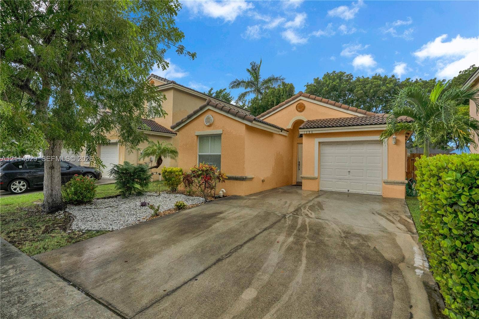 Stucco exterior featuring a tiled roof, arched entryway, single-car garage, and concrete driveway