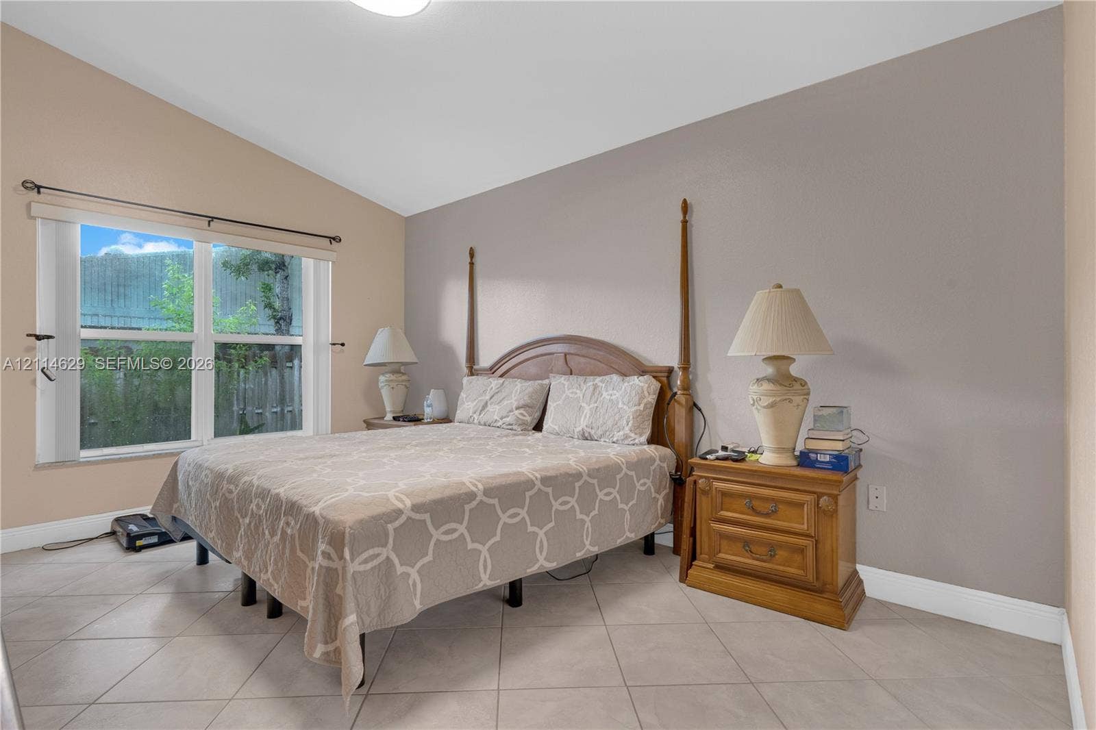 Room featuring vaulted ceilings, neutral wall tones, large window, and light-toned ceramic tile flooring