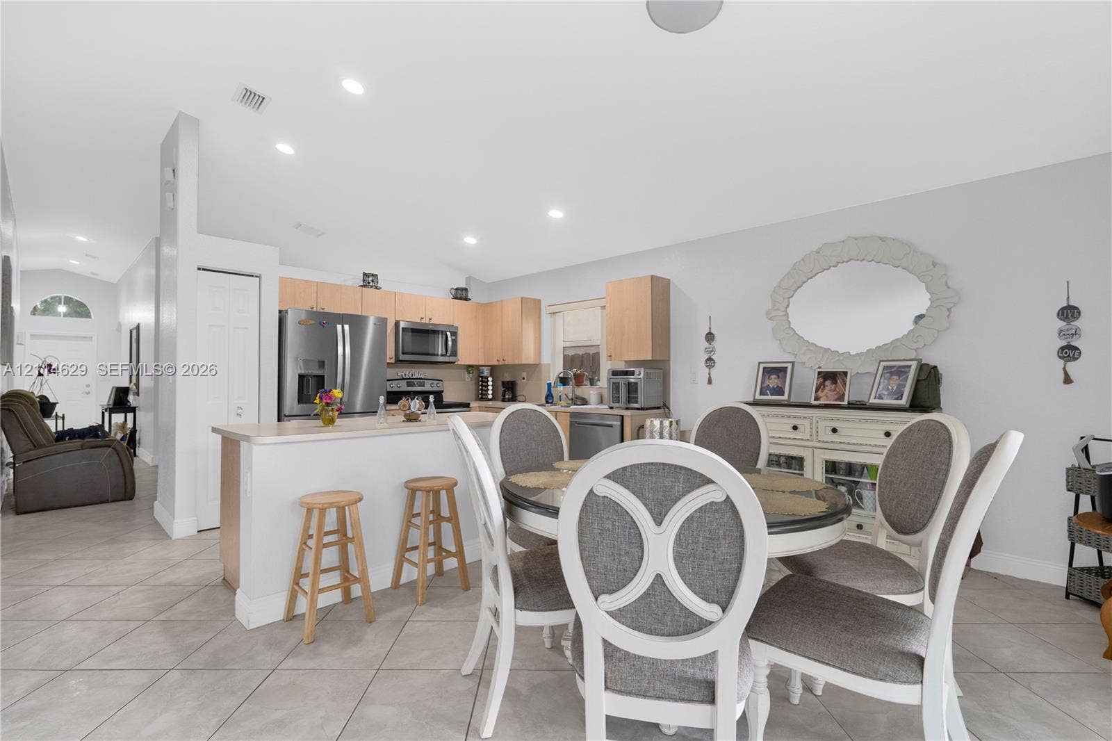 Kitchen featuring light-finish cabinetry, stainless steel appliances, a peninsula with a breakfast bar, recessed lighting, and tile flooring