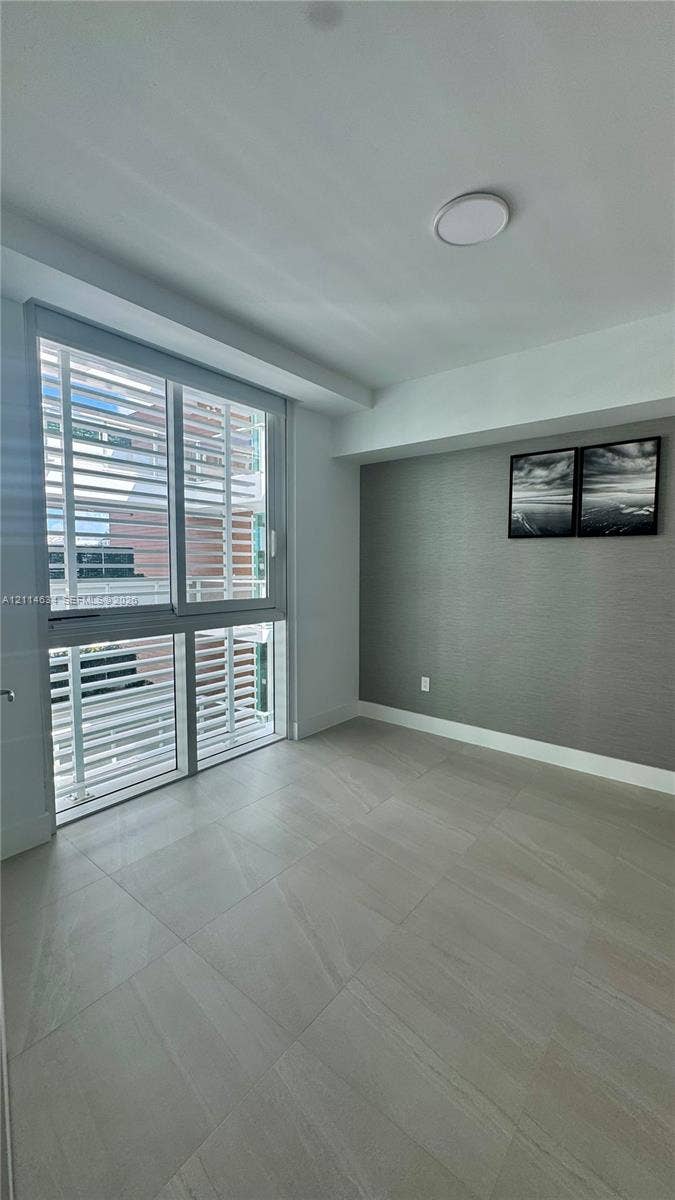 1150 102nd Street, #704, Bay Harbor Islands, Bay Harbor Islands, FL 33154 Large-format tile flooring, textured charcoal accent wall, floor-to-ceiling multi-panel window, and recessed ceiling lighting