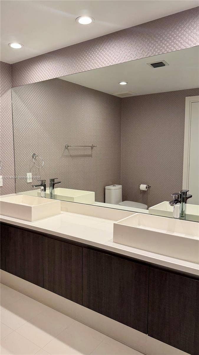 1150 102nd Street, #704, Bay Harbor Islands, Bay Harbor Islands, FL 33154 Floating vanity featuring dark wood-finish cabinetry, a dual-sink configuration with rectangular vessel basins, a continuous quartz countertop, and recessed ceiling lighting