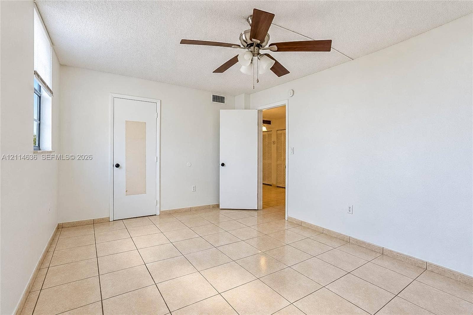 14155 SW 87th Street, #404-E, Miami, Miami, FL 33183 Interior space featuring neutral tile flooring, a multi-blade ceiling fan with integrated lighting, and a single-panel door with a central translucent inlay