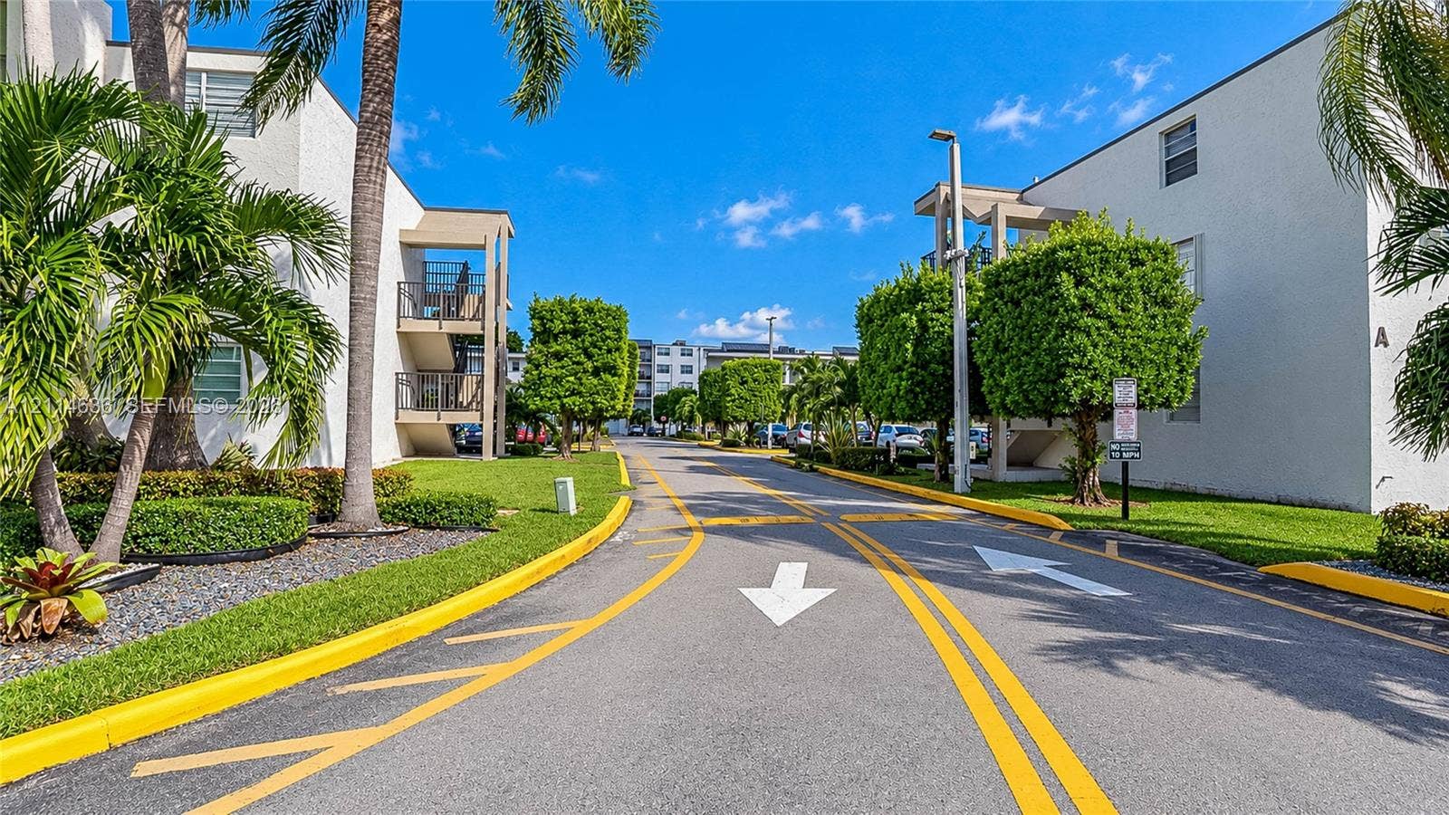 14155 SW 87th Street, #404-E, Miami, Miami, FL 33183 Multi-story exterior featuring a light-toned stucco facade, paved driveways, manicured hedges, and mature palm trees