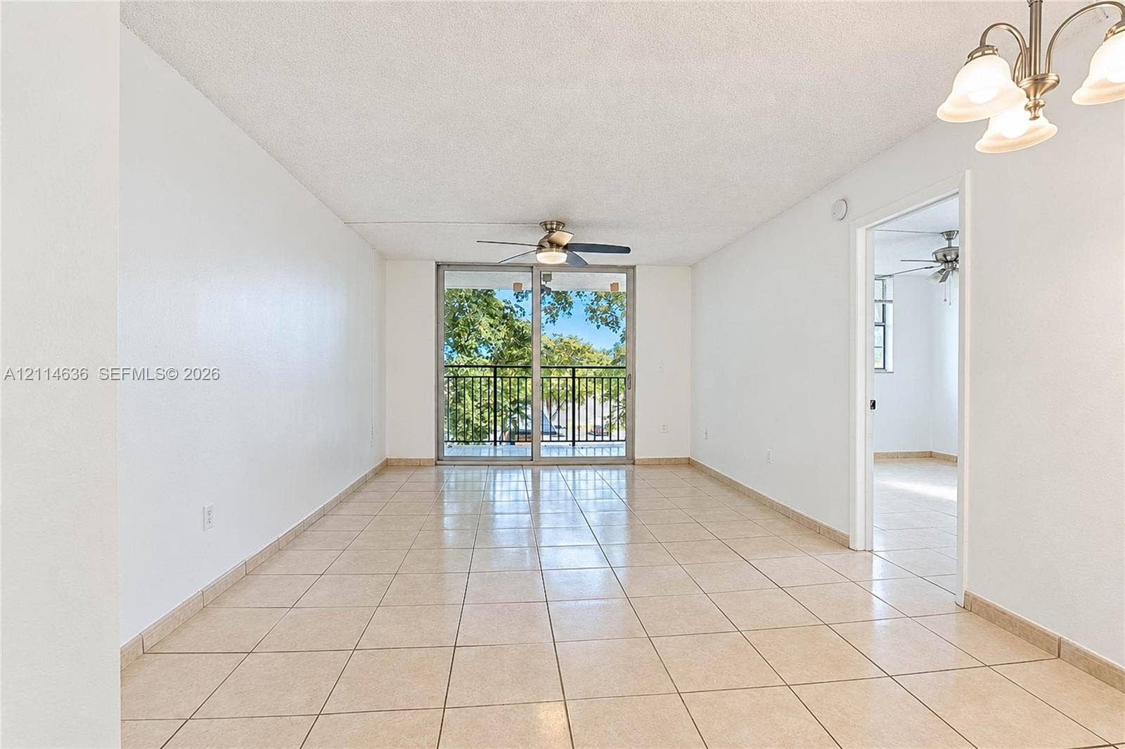 14155 SW 87th Street, #404-E, Miami, Miami, FL 33183 Interior space featuring large-format tile flooring, multi-light chandelier, ceiling fan, and sliding glass doors with a black metal balcony railing
