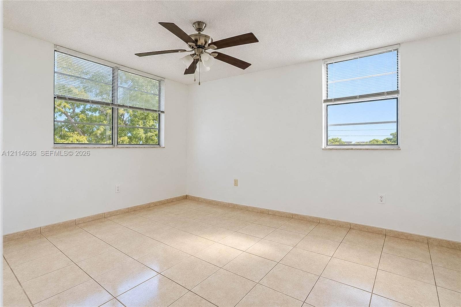 14155 SW 87th Street, #404-E, Miami, Miami, FL 33183 Light-filled room featuring neutral tile flooring, multi-pane windows, and a ceiling fan with integrated lighting