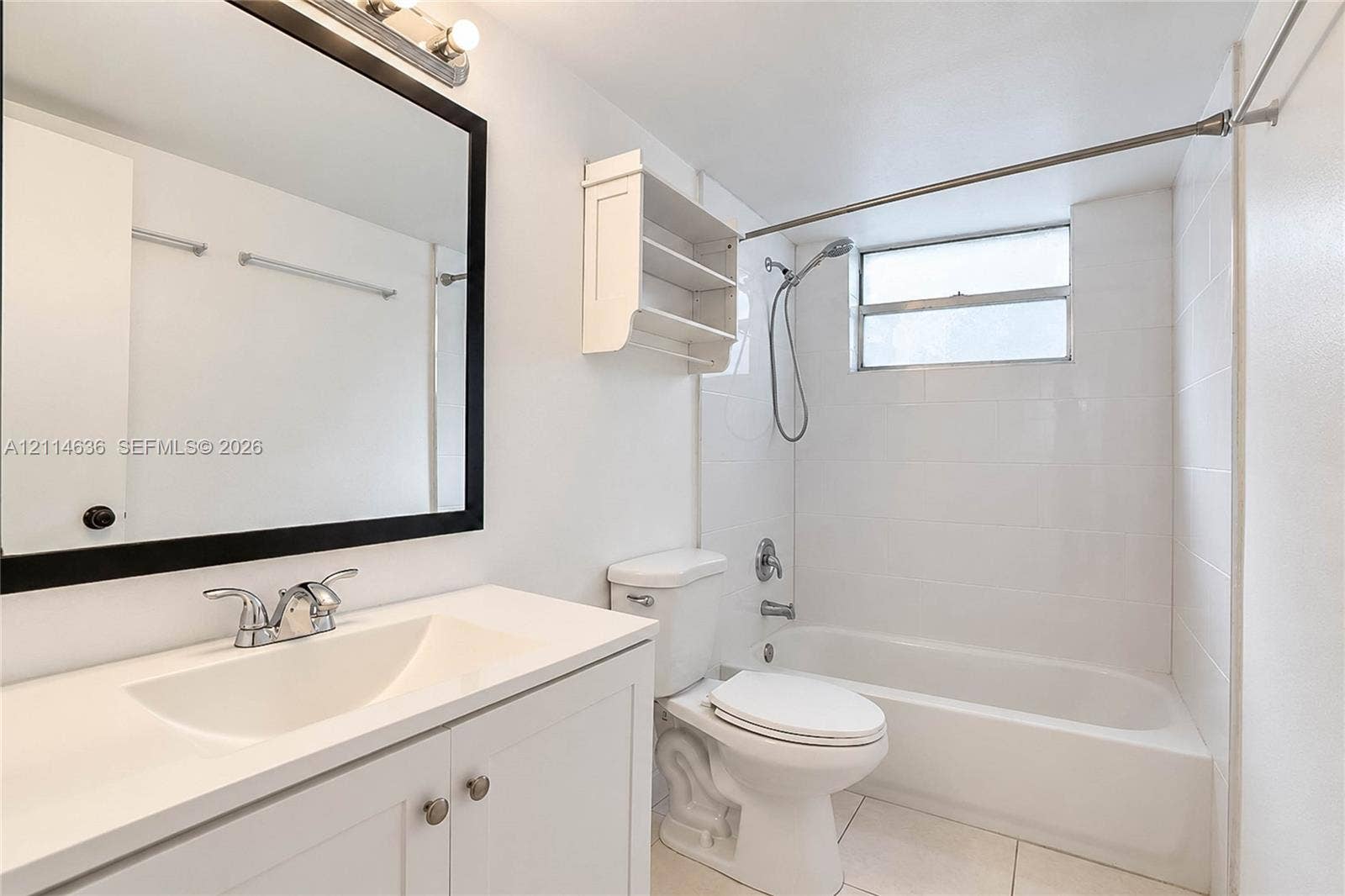 14155 SW 87th Street, #404-E, Miami, Miami, FL 33183 Bathroom featuring a vanity with an integrated sink, framed mirror, wall-mounted shelving, tiled tub surround, and a handheld shower fixture