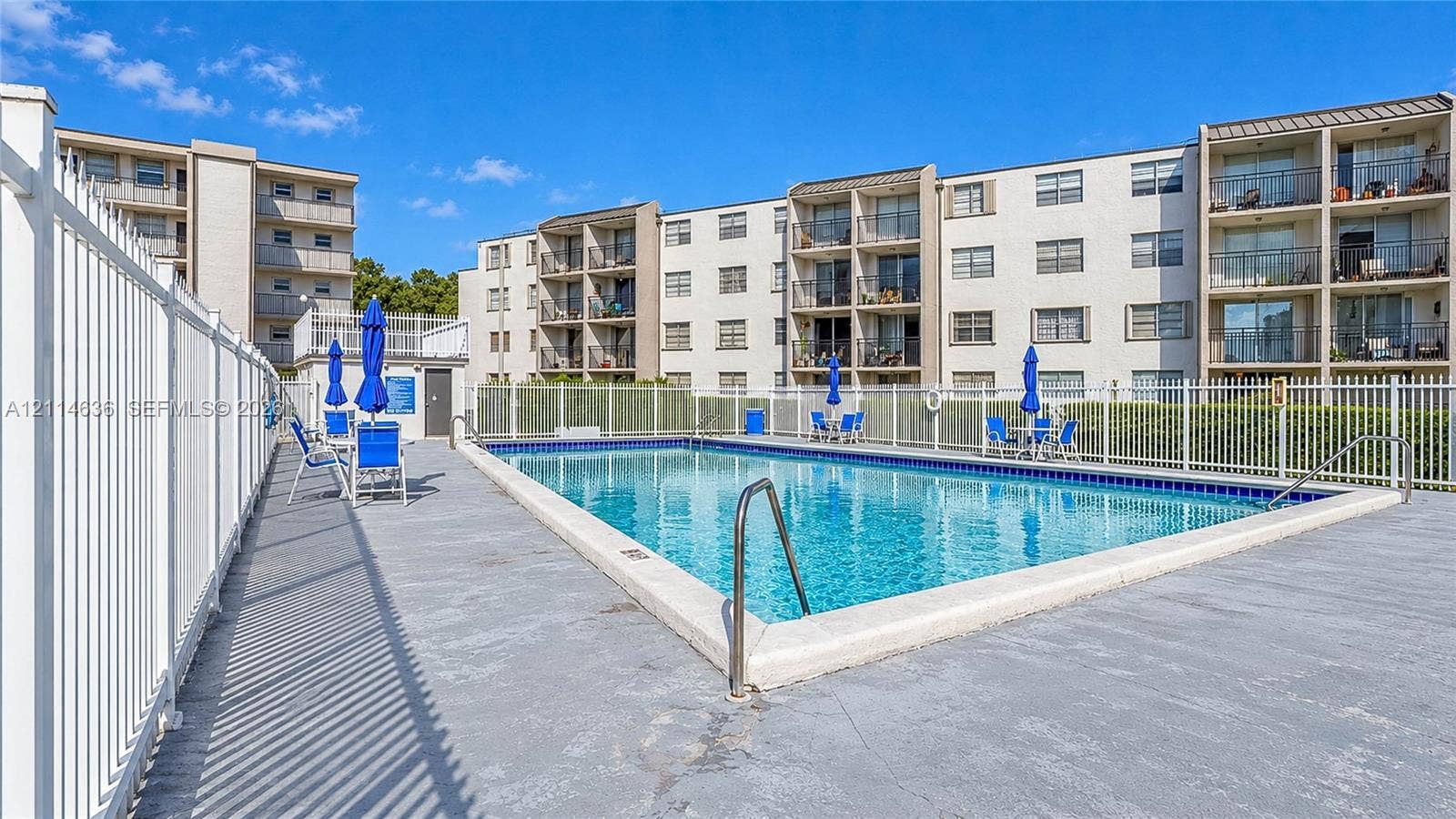 14155 SW 87th Street, #404-E, Miami, Miami, FL 33183 In-ground swimming pool featuring a concrete deck, white perimeter fencing, and metal handrails