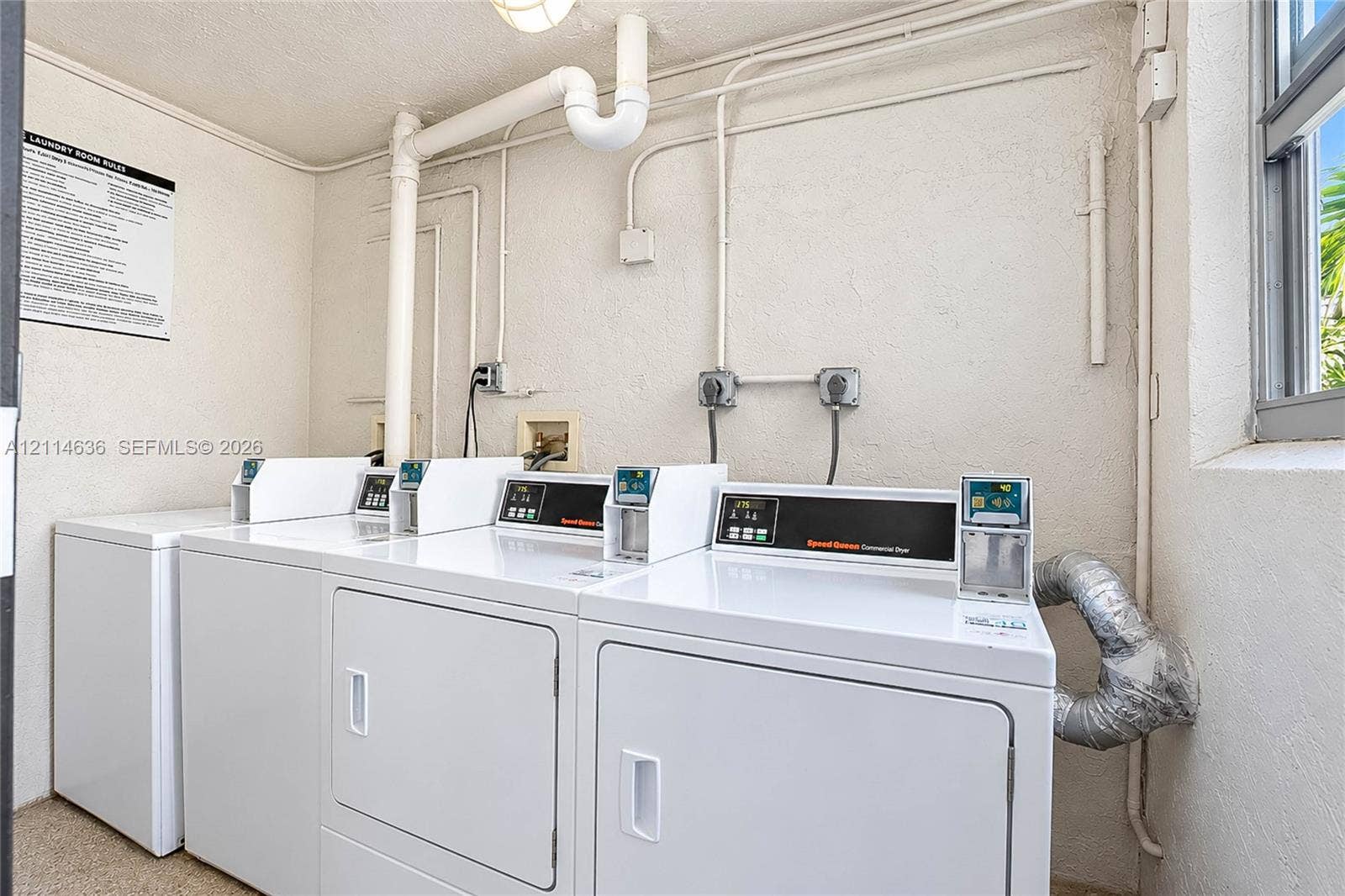 14155 SW 87th Street, #404-E, Miami, Miami, FL 33183 Laundry facility equipped with multiple commercial-grade dryers, wall-mounted electrical outlets, and a window