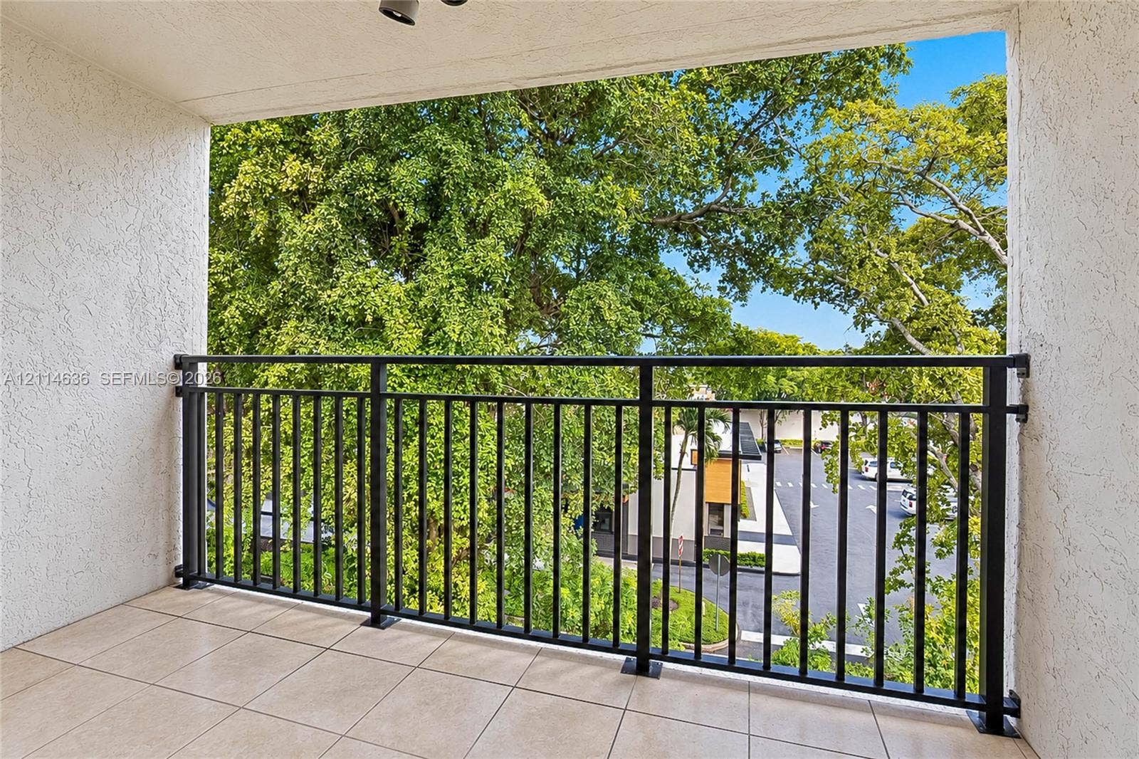 14155 SW 87th Street, #404-E, Miami, Miami, FL 33183 Covered balcony featuring neutral tile flooring, textured wall finishes, and a black metal railing