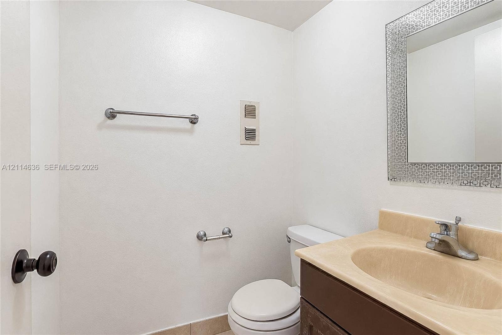 14155 SW 87th Street, #404-E, Miami, Miami, FL 33183 Vanity with a solid-surface countertop and integrated sink, complemented by a decorative framed mirror, dark-finish cabinetry, and polished metal hardware