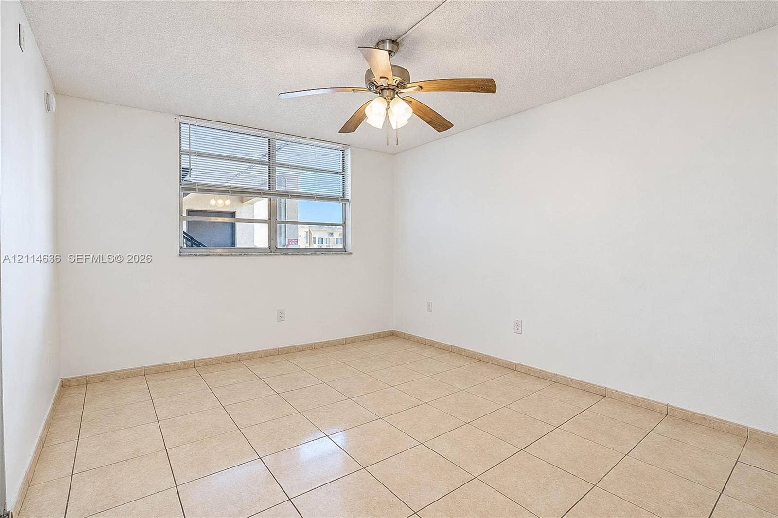 14155 SW 87th Street, #404-E, Miami, Miami, FL 33183 Room interior featuring neutral tile flooring, light-toned wall finishes, a multi-pane window, and a ceiling fan with integrated lighting