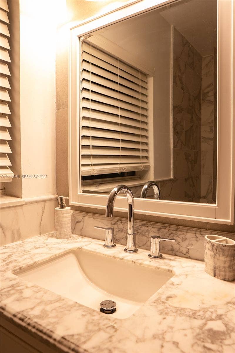 Stone countertop with an integrated undermount sink, polished chrome widespread faucet, and framed wall-mounted mirror