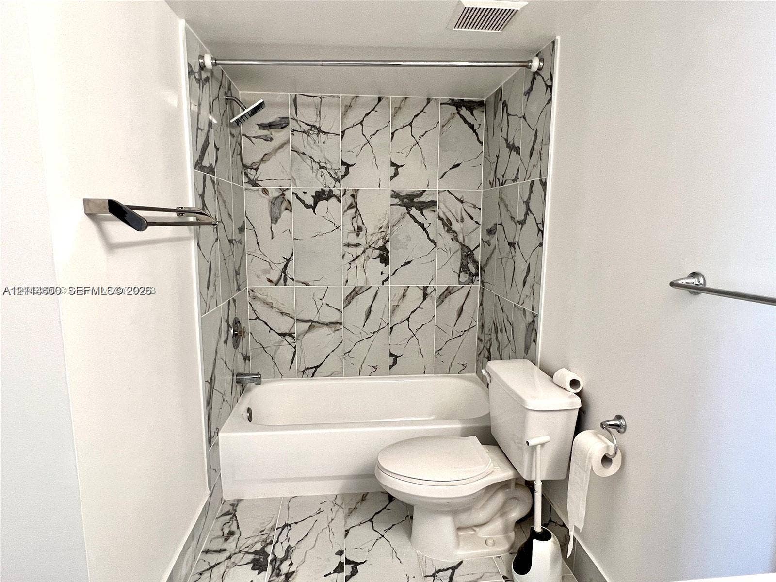 1450 SE 3rd Avenue, #411, Dania, Dania Beach, FL 33004 Full-height wall tiling with a high-contrast vein pattern, built-in bathtub, and chrome-finish fixtures