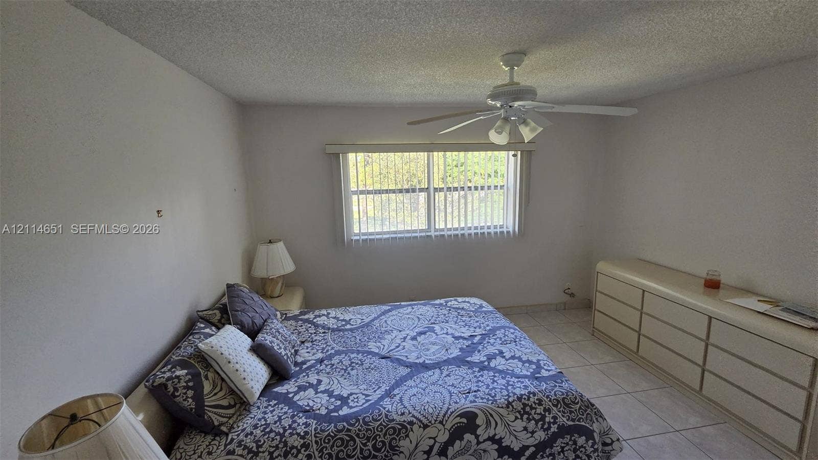 Interior room featuring tile flooring, a central ceiling fan with integrated lighting, and a window with vertical blinds