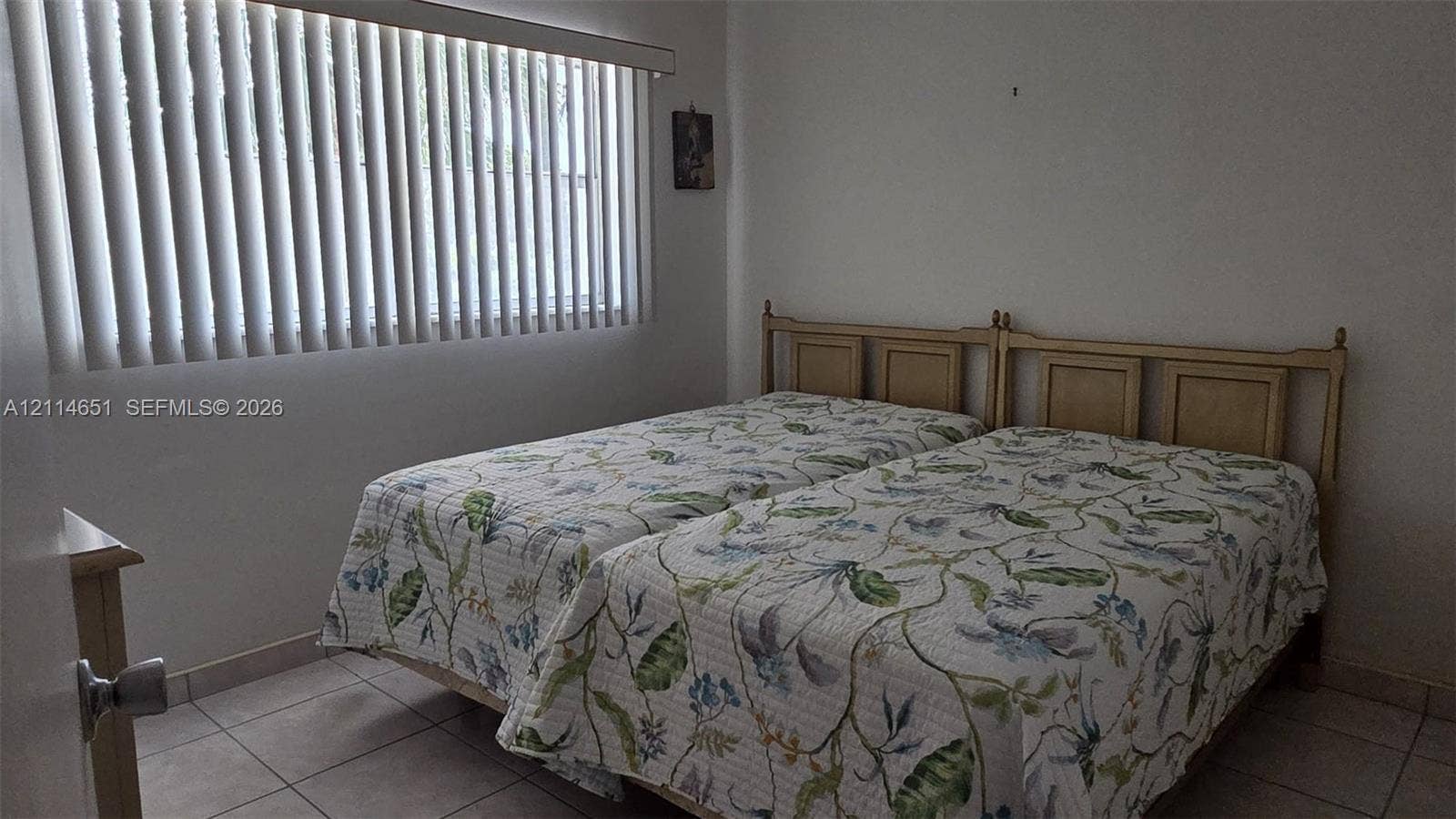 Interior room featuring neutral wall finishes, tile flooring, and vertical window blinds