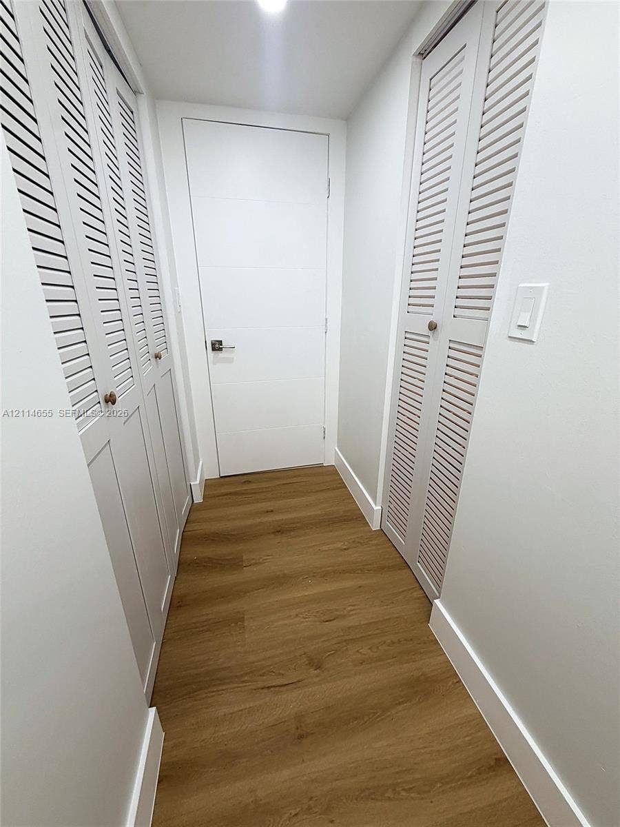 3301 N Country Club Drive, #507, Aventura, Aventura, FL 33180 White vanity with multiple drawers and cabinets featuring matte black hardware, large-format tile flooring, frameless glass walk-in shower with stone-finish surround, and expansive wall-mounted mirror