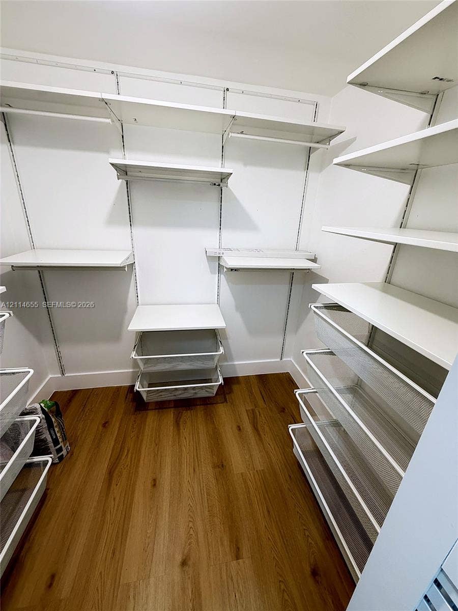 3301 N Country Club Drive, #507, Aventura, Aventura, FL 33180 Light-toned wood-finish flooring, six-light multi-arm ceiling fixture with frosted glass shades, and bi-fold closet doors