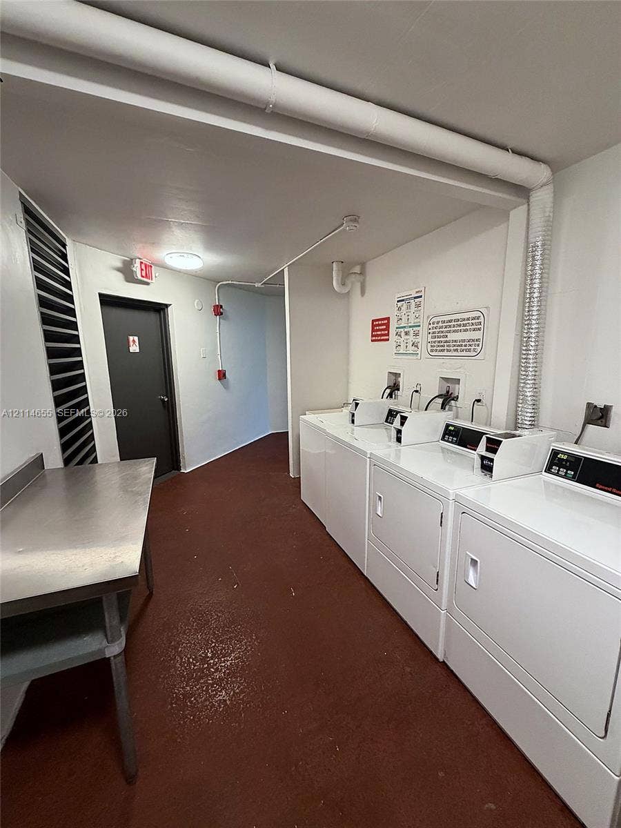 3301 N Country Club Drive, #507, Aventura, Aventura, FL 33180 Laundry room featuring multiple white front-loading clothes washers and dryers, a stainless steel folding table, and solid-surface flooring
