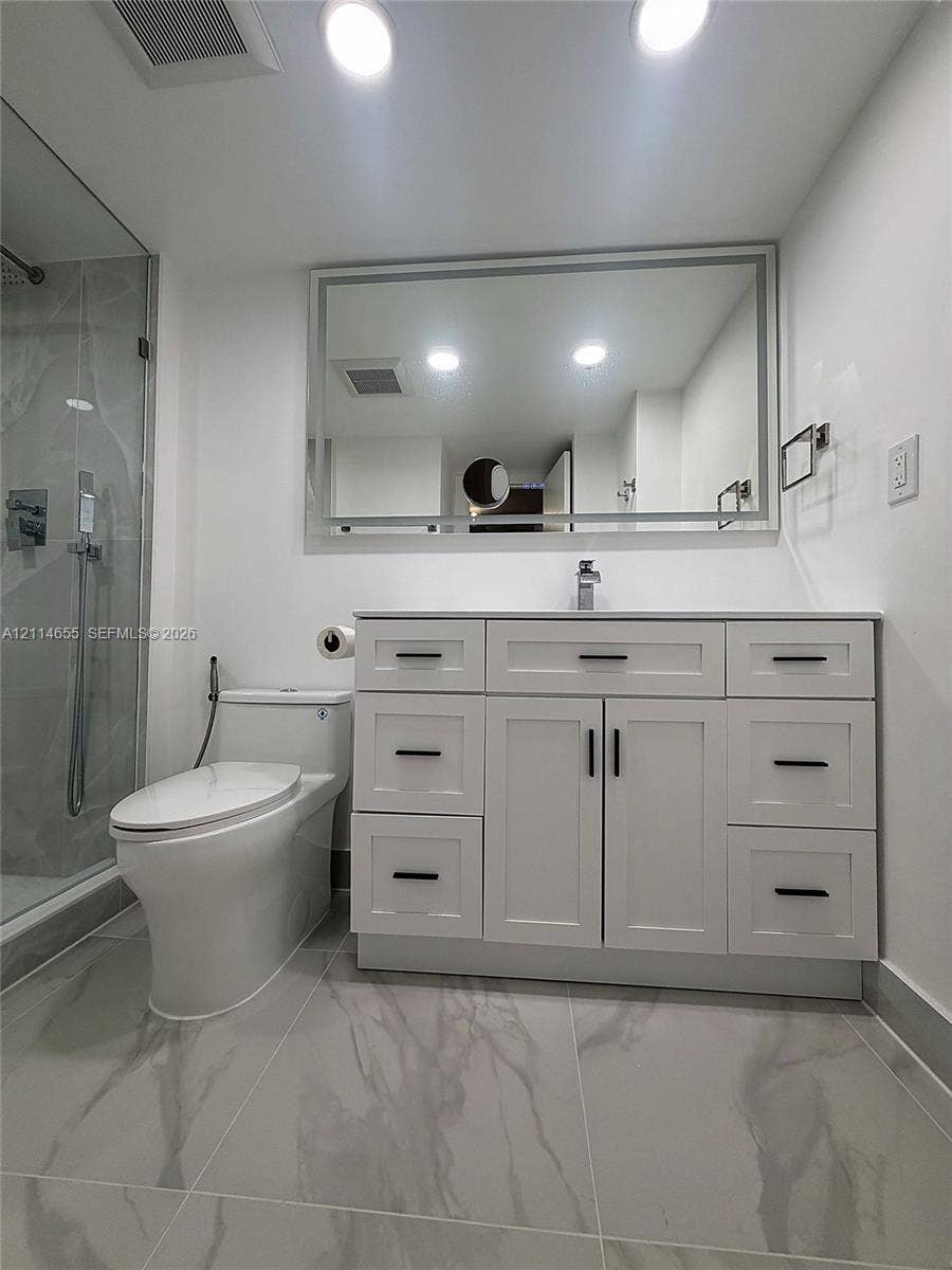 3301 N Country Club Drive, #507, Aventura, Aventura, FL 33180 Walk-in shower featuring large-format stone-finish tile surround, frameless glass enclosure, rainfall showerhead, and hexagonal floor tiling